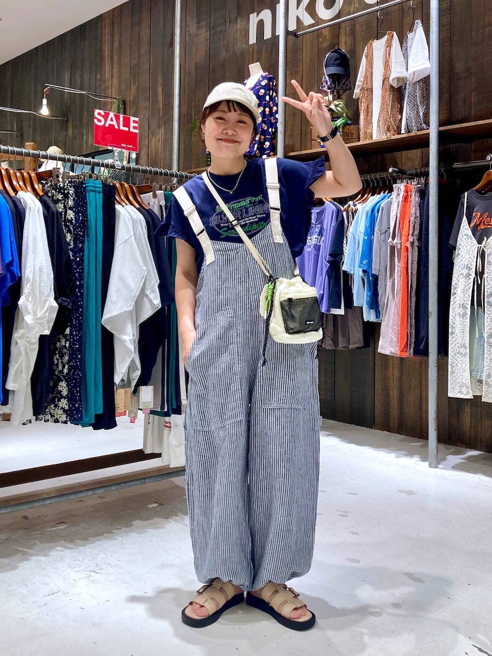 ブルー系のサロペット/オーバーオール、ブルー系のTシャツ/カットソー、ベージュ系のショルダーバッグを着用したレディースの夏コーディネートの2枚目の写真