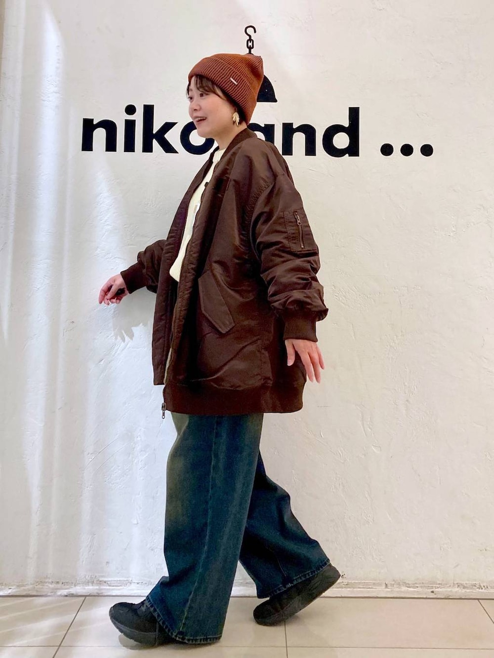 レッド系のMA-1、ベージュ系のニット/セーター、オレンジ系のニットキャップ/ビーニーを着用したレディースの秋コーディネートの3枚目の写真