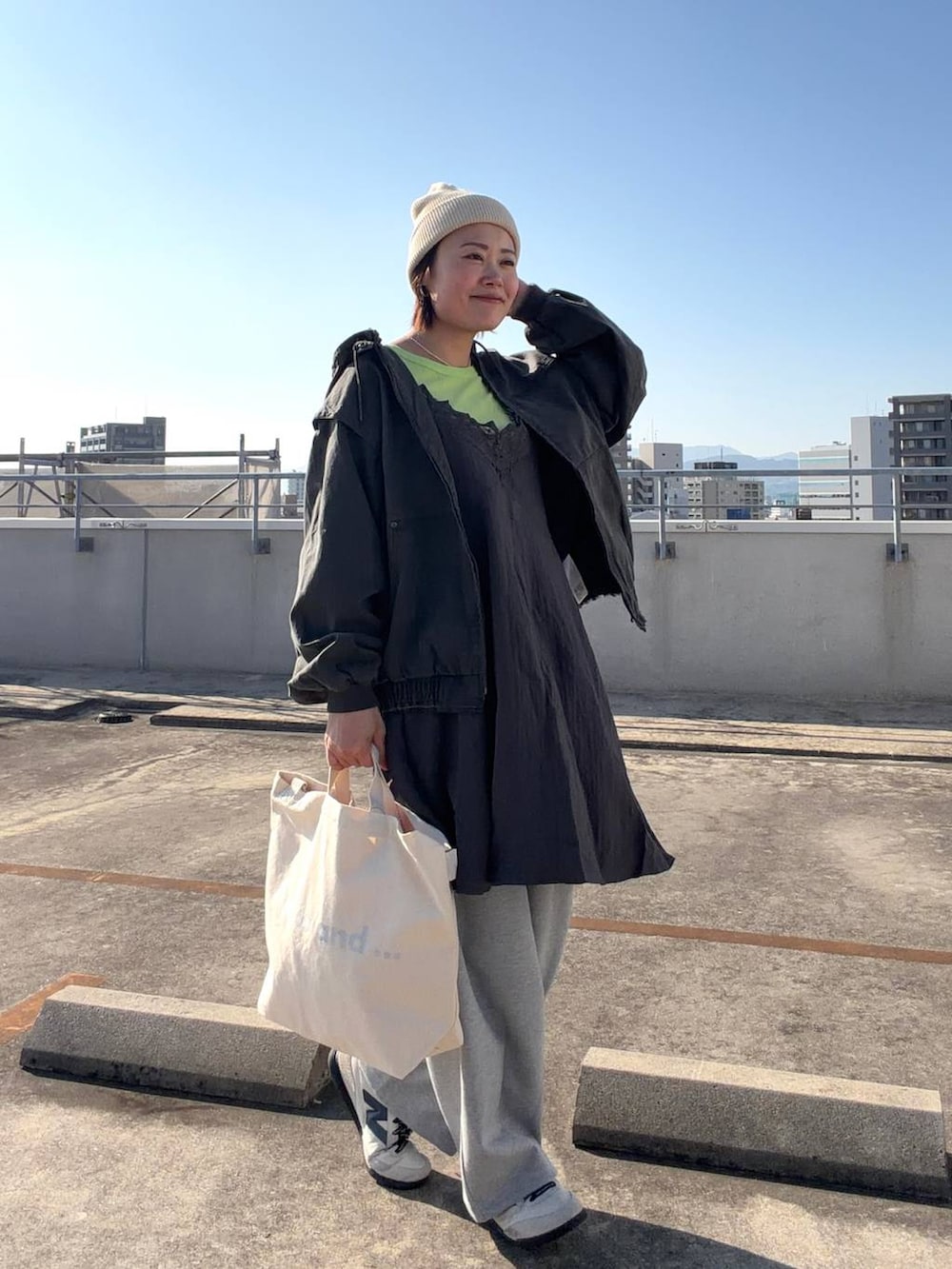 ホワイト系のトートバッグ、ブラック系のブルゾン、グレー系のワンピースを着用したレディースの冬コーディネートの2枚目の写真