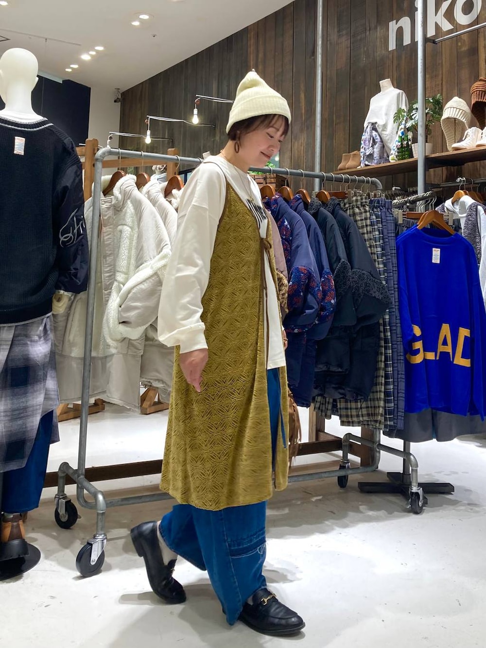 ブルー系のデニムパンツ、ブラウン系のショルダーバッグ、イエロー系のワンピースを着用したレディースの秋コーディネートの5枚目の写真