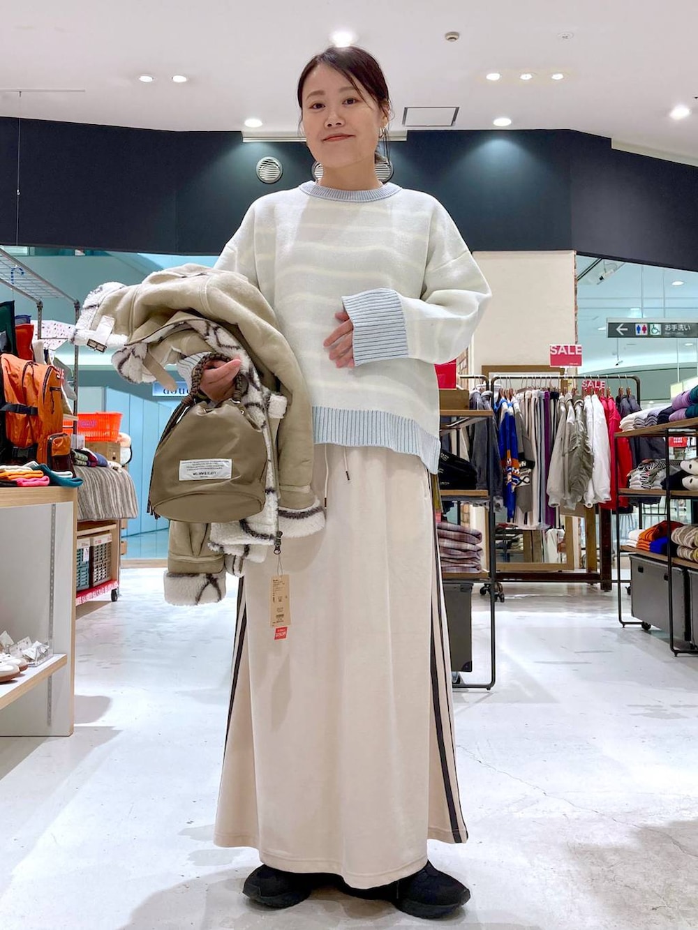 ベージュ系のニット/セーター、グリーン系のショルダーバッグ、ベージュ系のムートンコートを着用したレディースの冬コーディネートの3枚目の写真