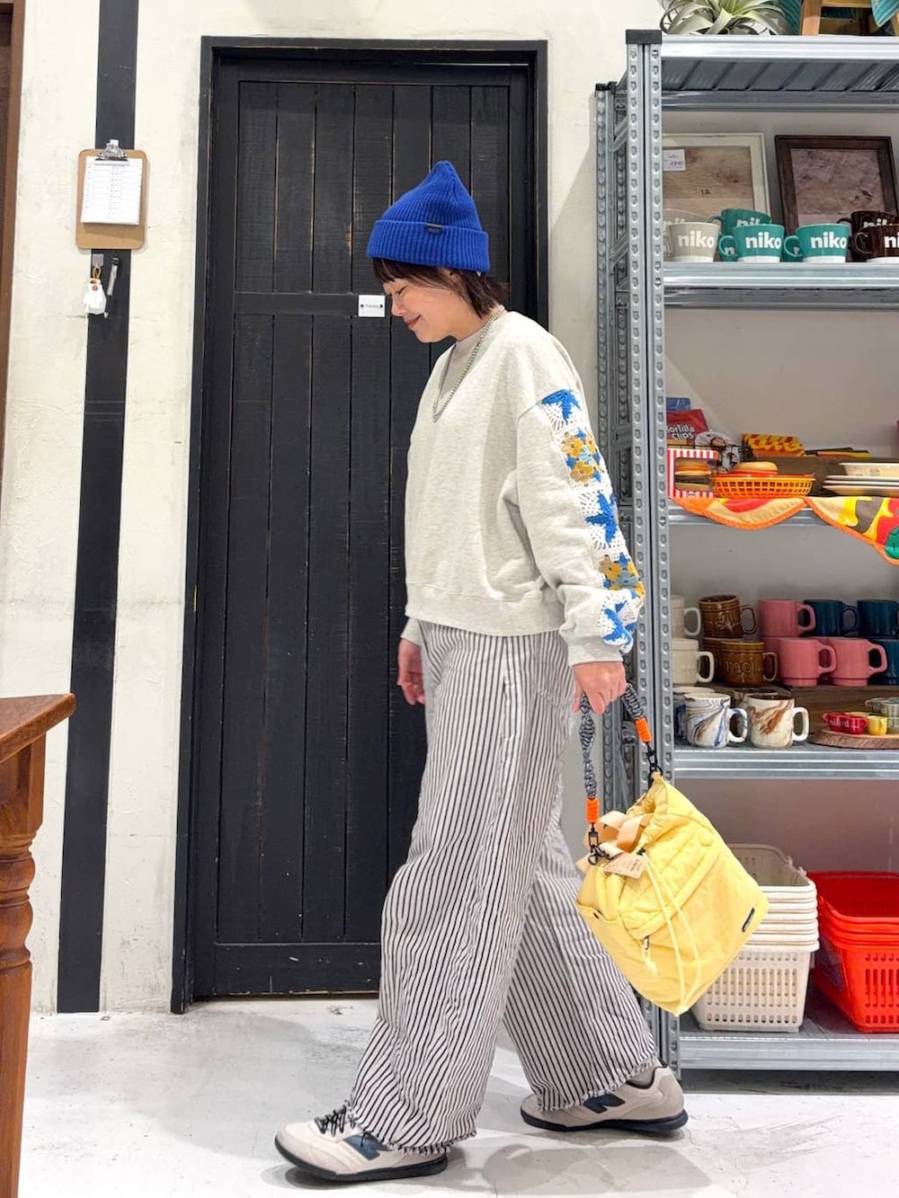 イエロー系のショルダーバッグ、ホワイト系のデニムパンツ、ブルー系のニットキャップ/ビーニーを着用したレディースの冬コーディネートの3枚目の写真