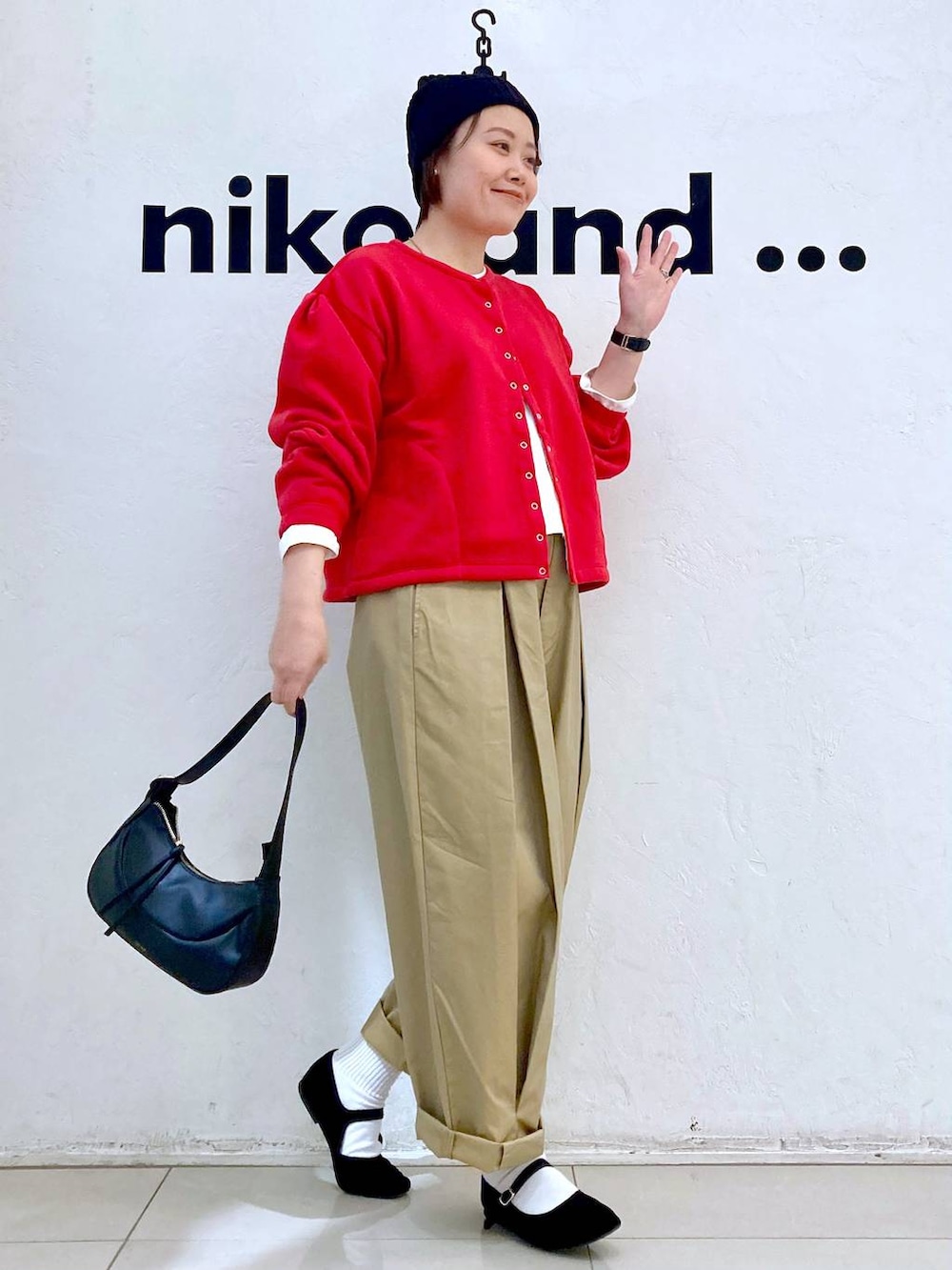ブラック系のショルダーバッグ、ブラック系のパンプス、イエロー系のチノパンツを着用したレディースの冬コーディネートの2枚目の写真