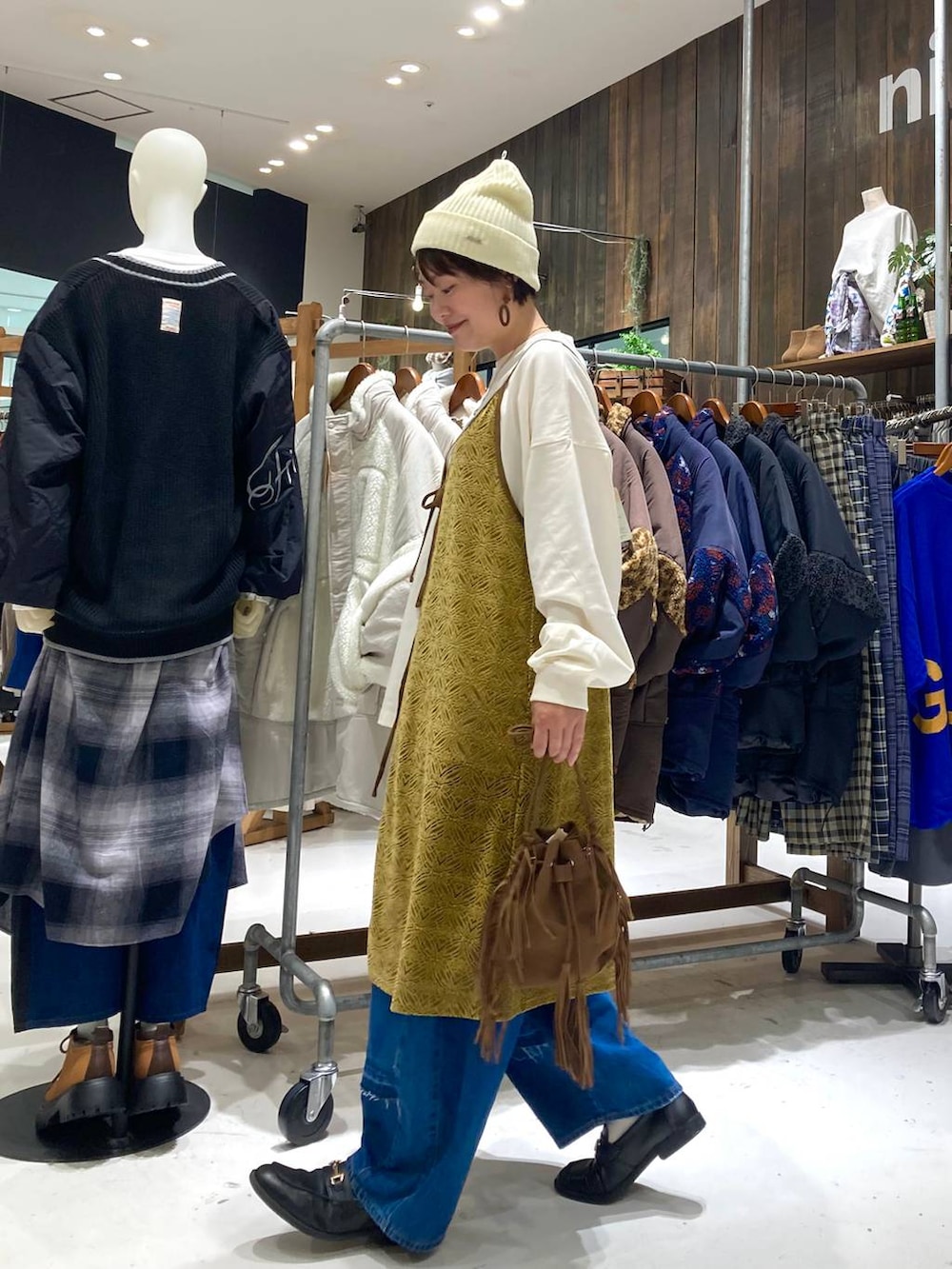 ブルー系のデニムパンツ、ブラウン系のショルダーバッグ、イエロー系のワンピースを着用したレディースの秋コーディネートの3枚目の写真