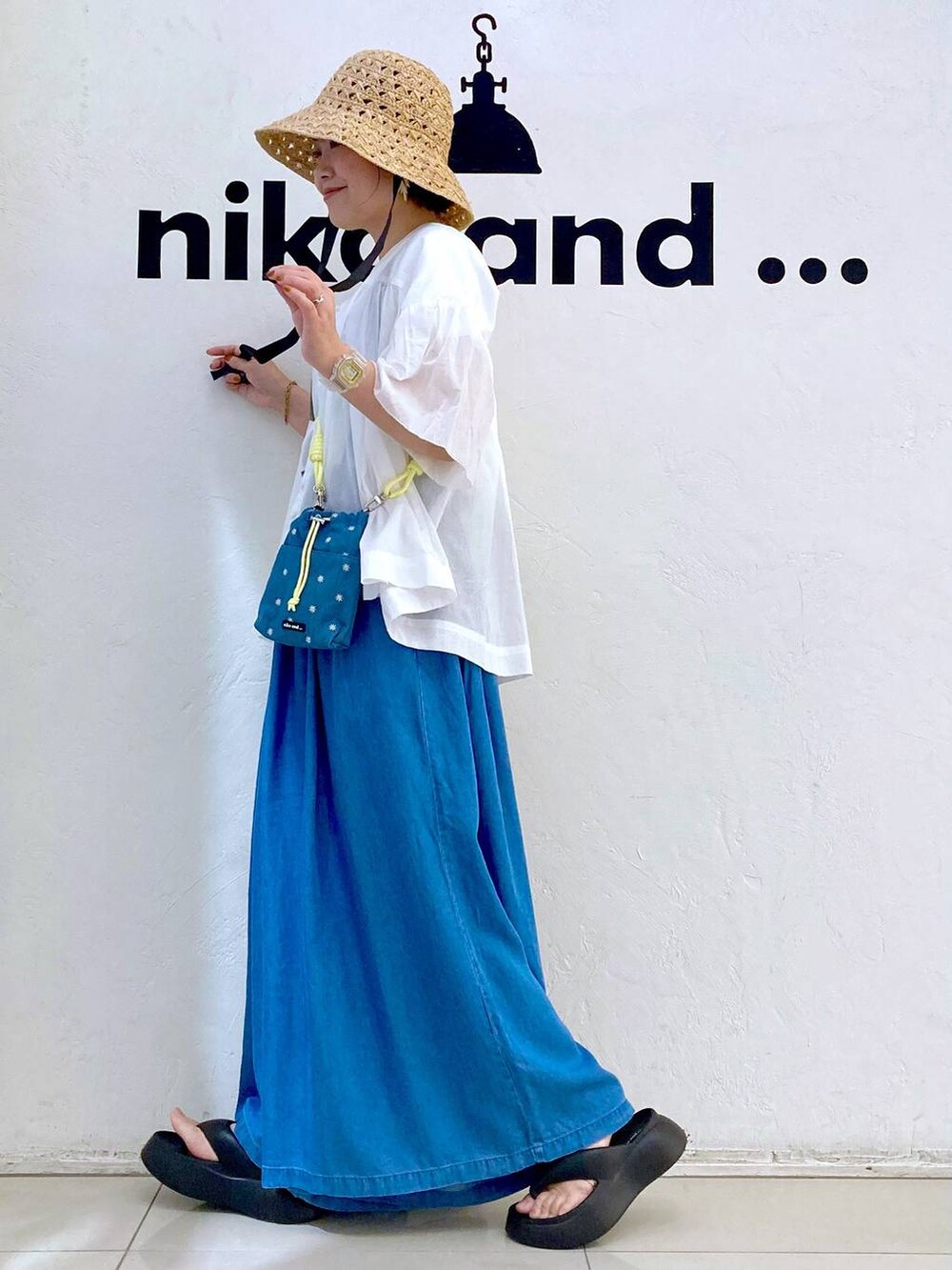 ブルー系のショルダーバッグ、ブラック系のサンダル、ブルー系のデニムパンツを着用したレディースの春コーディネートの3枚目の写真