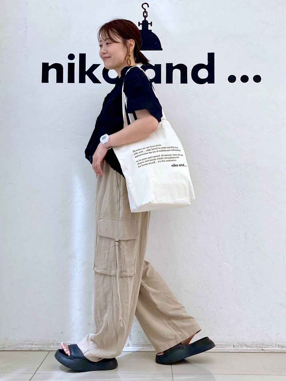 ブラック系のサンダル、ベージュ系のカーゴパンツ、ベージュ系のトートバッグを着用したレディースの夏コーディネートの3枚目の写真