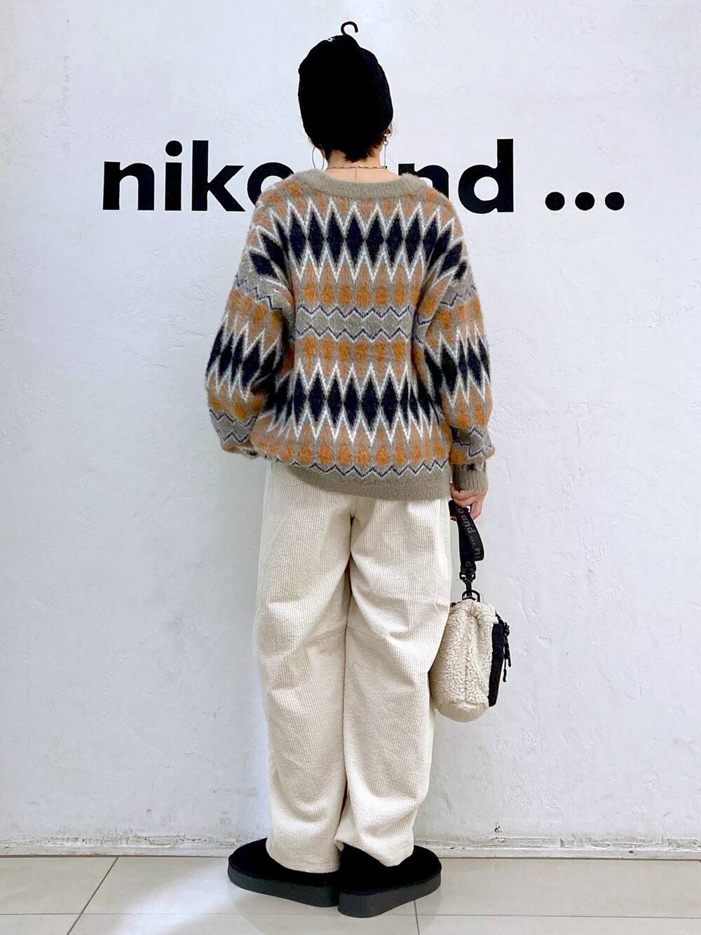 ブラウン系のカーディガン/ボレロ、ブラック系のブーツ、ベージュ系のショルダーバッグを着用したレディースの冬コーディネートの3枚目の写真