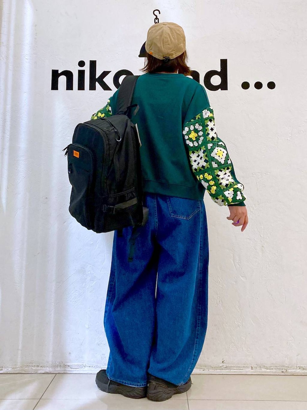 グリーン系のスウェット、ブルー系のデニムパンツ、ブラック系のバックパック/リュックを着用したレディースの秋コーディネートの4枚目の写真