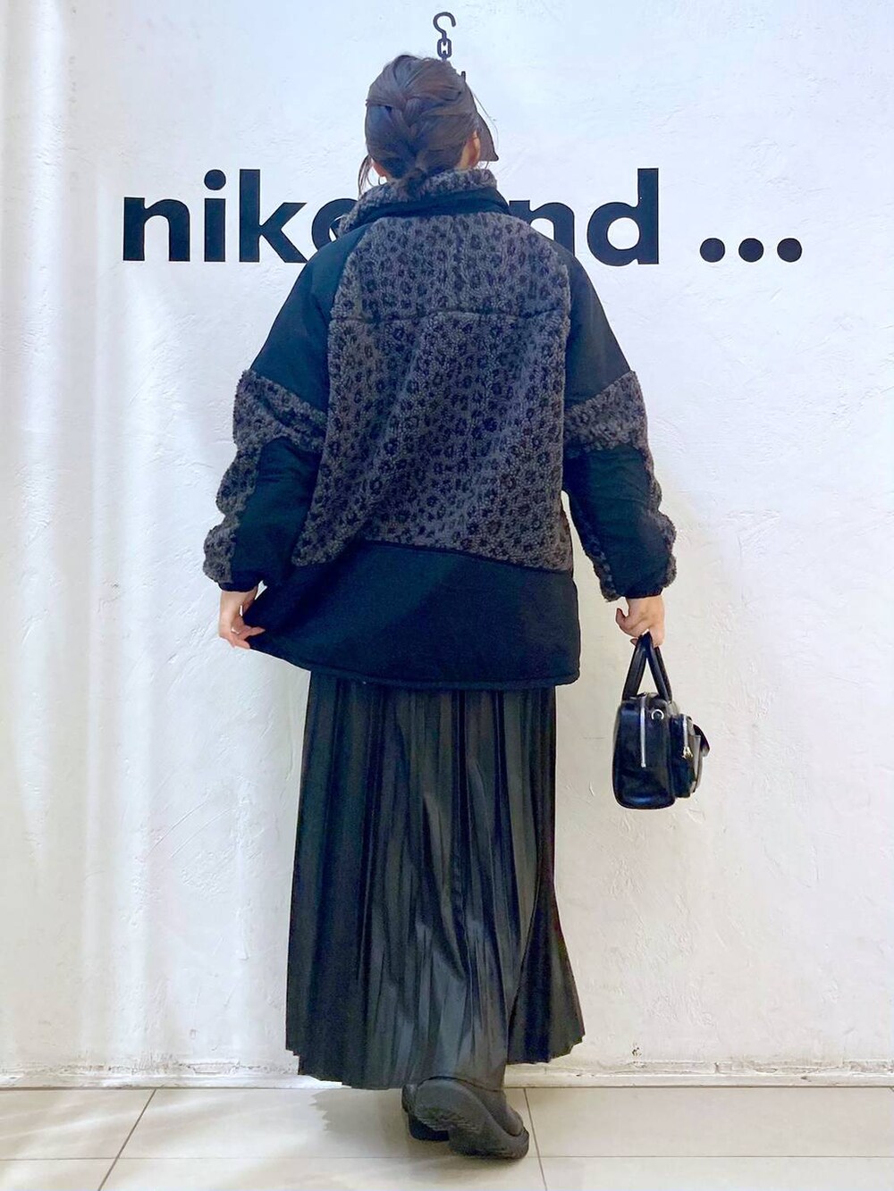 ブラック系のニット/セーター、ブラック系のスカート、ブラック系のショルダーバッグを着用したレディースの秋コーディネートの5枚目の写真