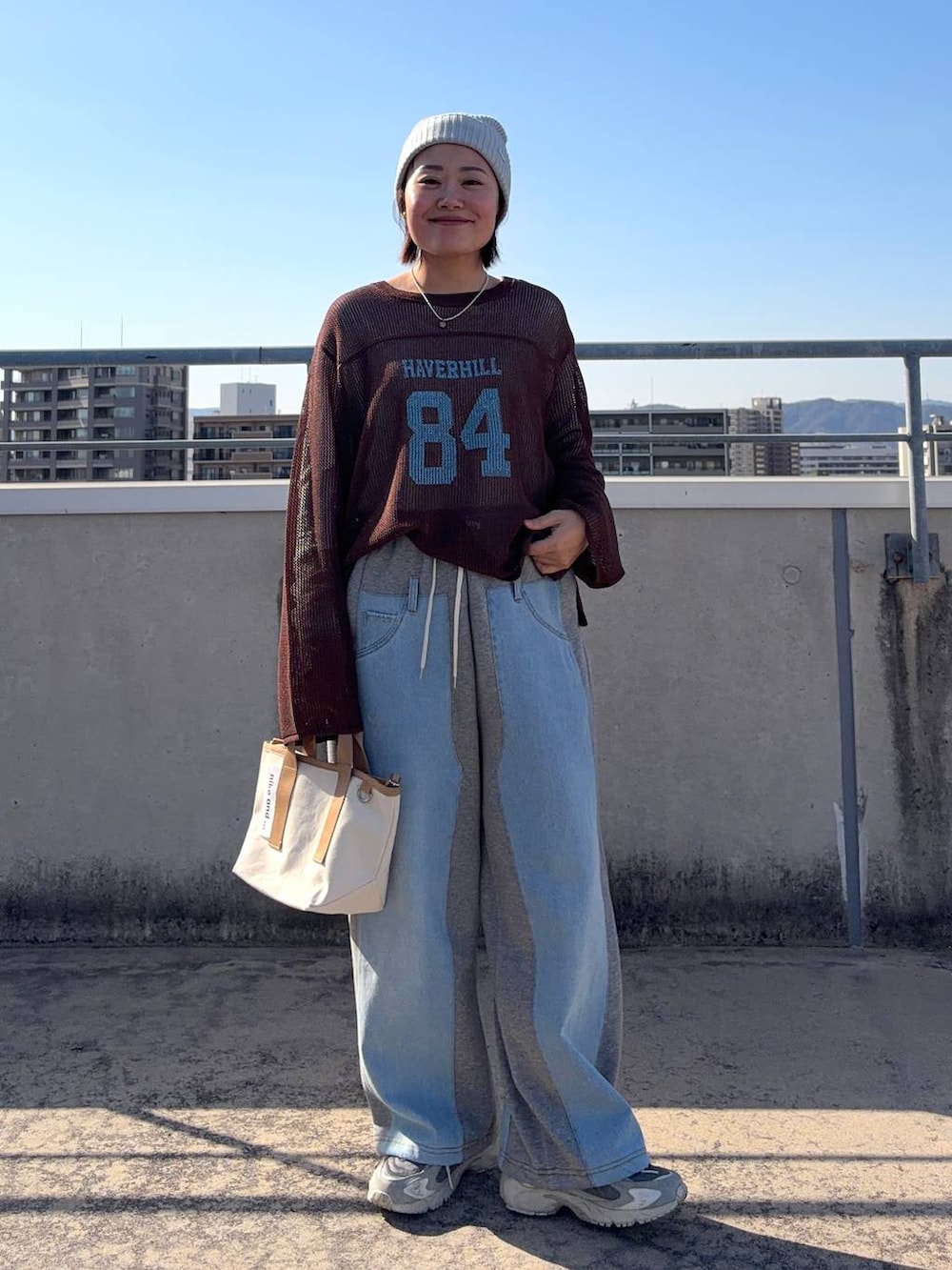 グレー系のデニムパンツ、ホワイト系のTシャツ/カットソー、その他のショルダーバッグを着用したレディースの春コーディネートの6枚目の写真