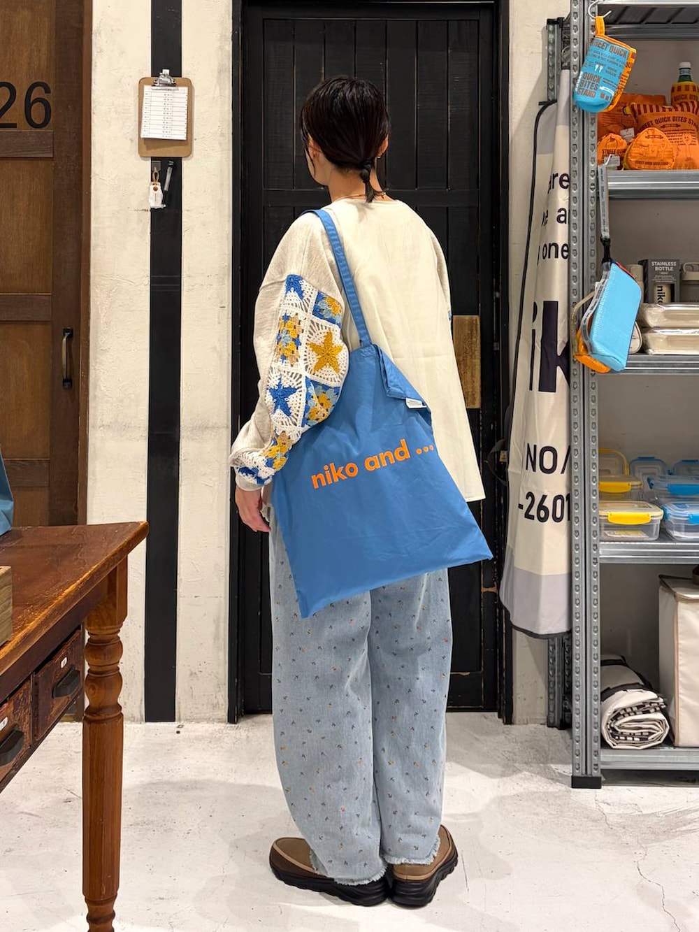 ベージュ系のスウェット、ブルー系のトートバッグ、ブルー系のデニムパンツを着用したレディースの春コーディネートの4枚目の写真