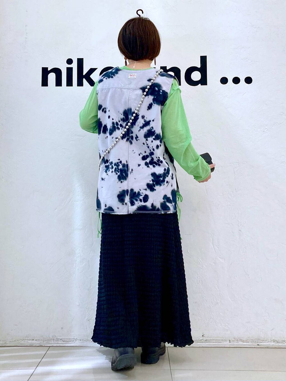 ブルー系のベスト、ブラック系のスカート、グリーン系のTシャツ/カットソーを着用したレディースの春コーディネートの4枚目の写真