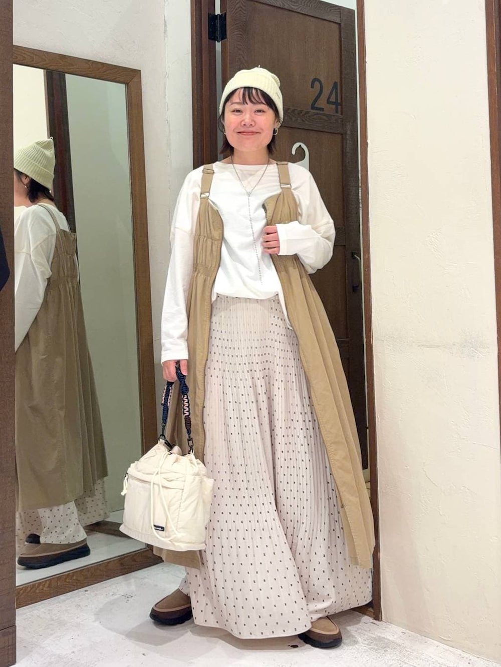 ベージュ系のジャンパースカート、ベージュ系のその他シューズ、ホワイト系のTシャツ/カットソーを着用したレディースの冬コーディネートの5枚目の写真