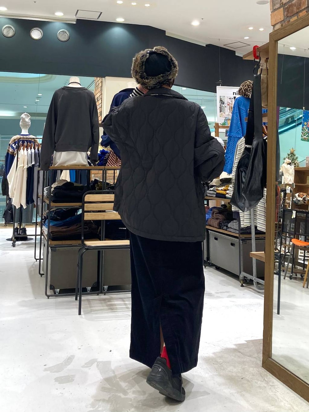 ブラック系のその他アウター、ホワイト系のニット/セーター、ブラック系のショルダーバッグを着用したレディースの冬コーディネートの6枚目の写真