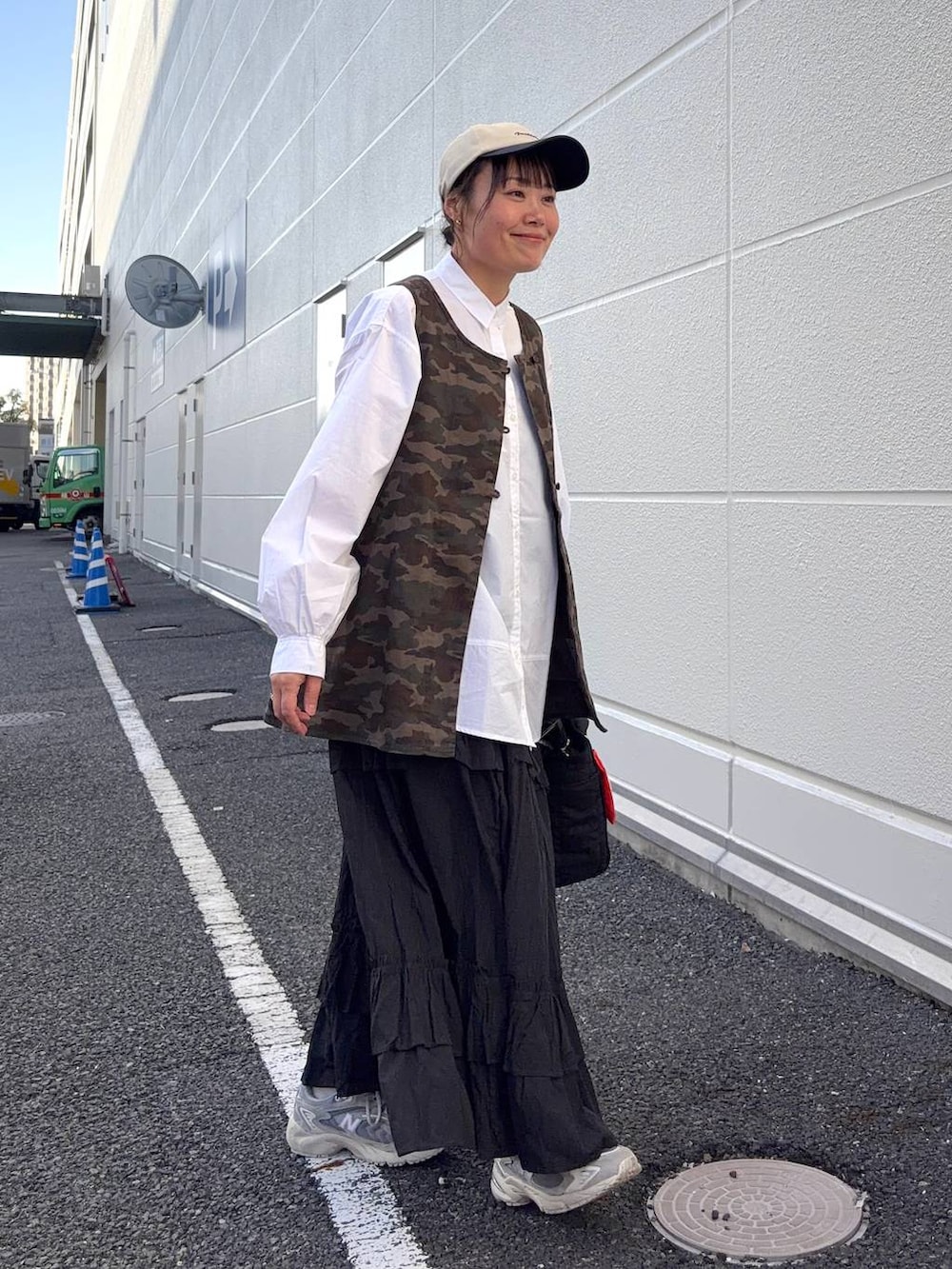 ブラック系のトートバッグ、ブラウン系のベスト、ホワイト系のシャツ/ブラウスを着用したレディースの春コーディネートの5枚目の写真