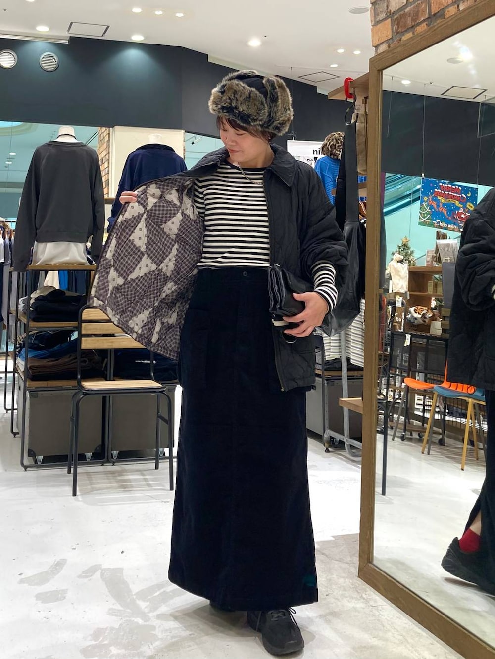 ブラック系のその他アウター、ホワイト系のニット/セーター、ブラック系のショルダーバッグを着用したレディースの冬コーディネートの3枚目の写真