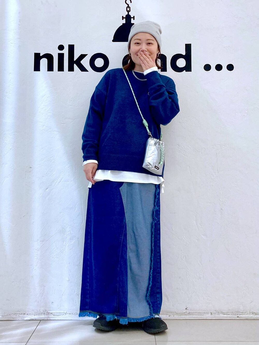 シルバー系のショルダーバッグ、ブルー系のデニムスカート、ブルー系のニット/セーターを着用したレディースの冬コーディネートの2枚目の写真