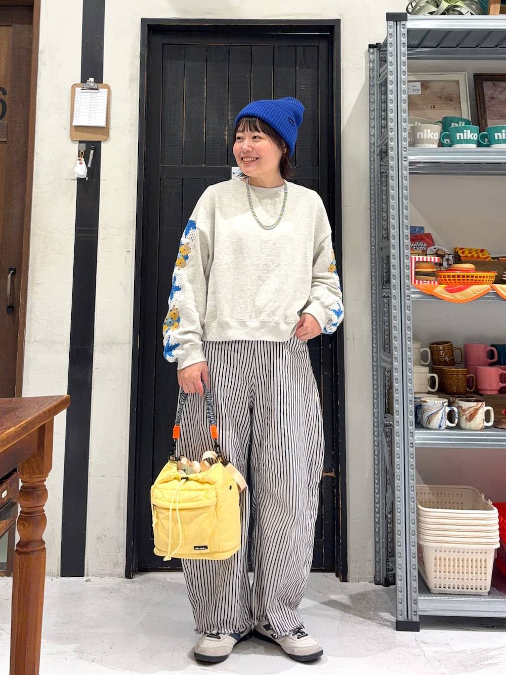 イエロー系のショルダーバッグ、ホワイト系のデニムパンツ、ブルー系のニットキャップ/ビーニーを着用したレディースの冬コーディネートの2枚目の写真