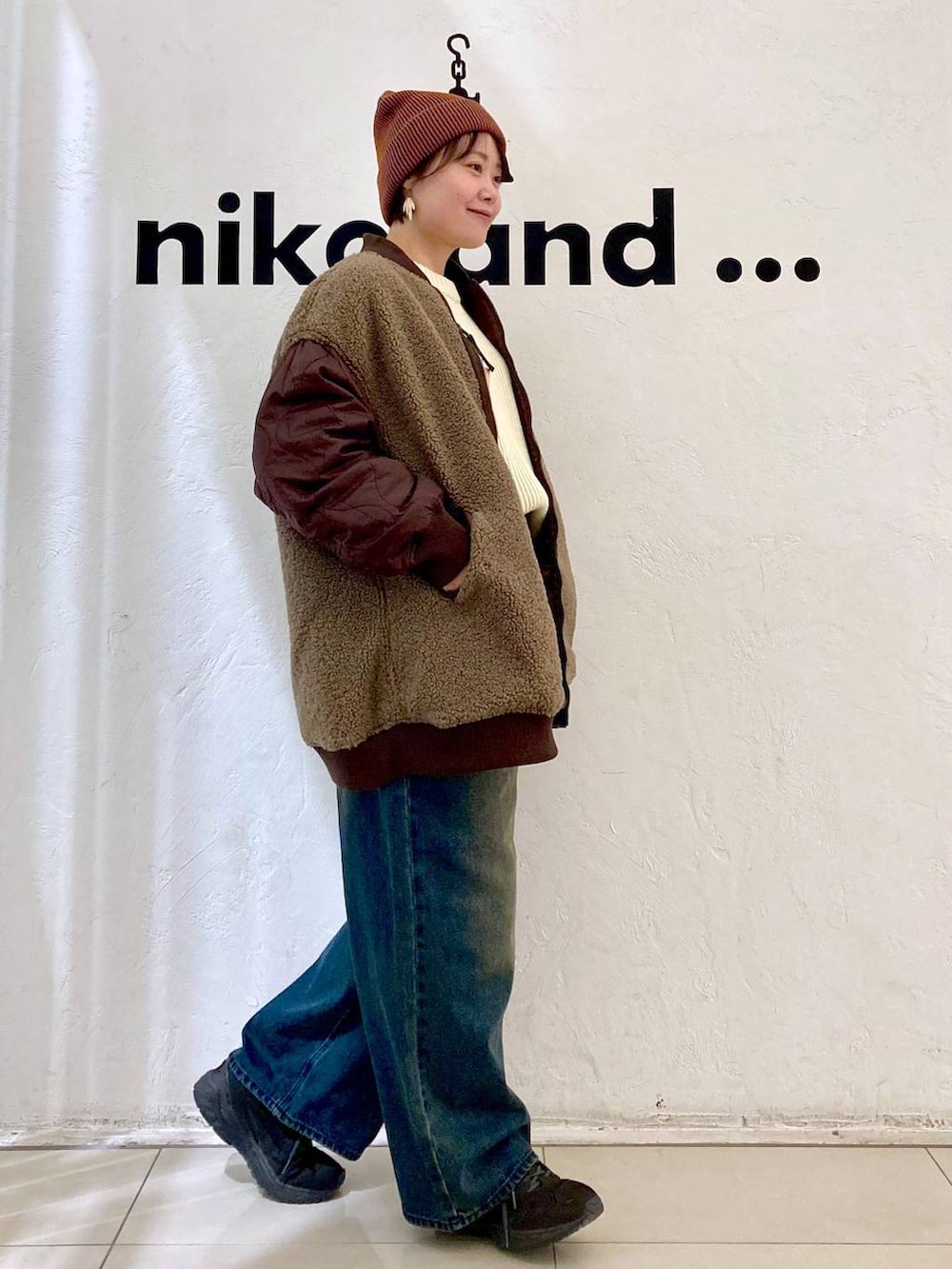 レッド系のMA-1、ベージュ系のニット/セーター、オレンジ系のニットキャップ/ビーニーを着用したレディースの秋コーディネートの6枚目の写真