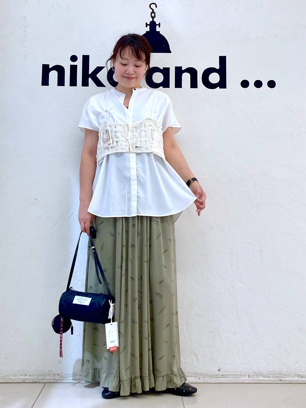 ブラック系のパンプス、ブラック系のショルダーバッグ、グリーン系のスカートを着用したレディースの夏コーディネートの2枚目の写真