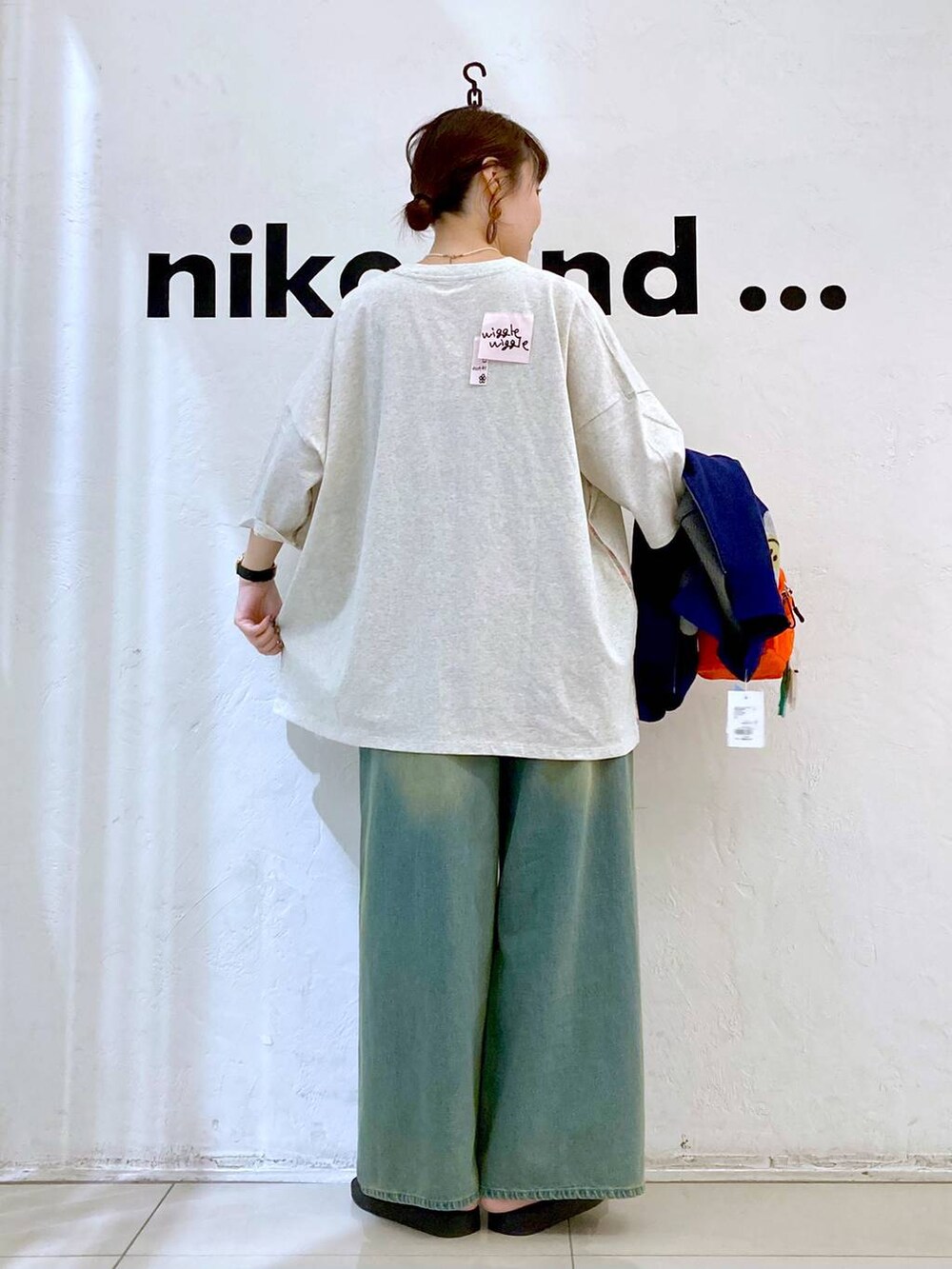 オレンジ系のショルダーバッグ、ベージュ系のTシャツ/カットソー、ブルー系のデニムパンツを着用したレディースの夏コーディネートの3枚目の写真