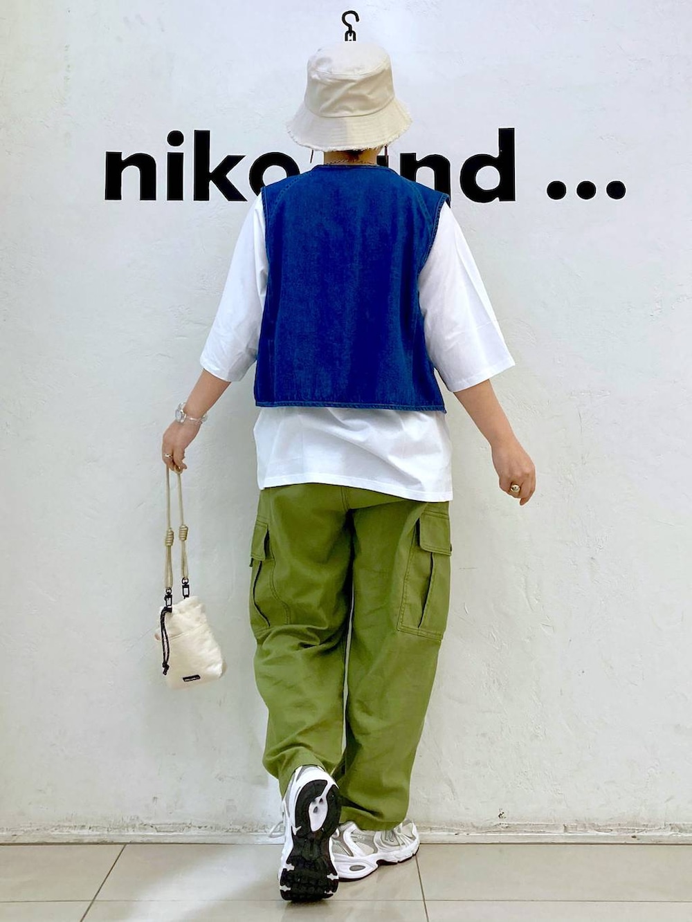 ブルー系のベスト、ベージュ系のショルダーバッグ、グリーン系のカーゴパンツを着用したレディースの春コーディネートの4枚目の写真