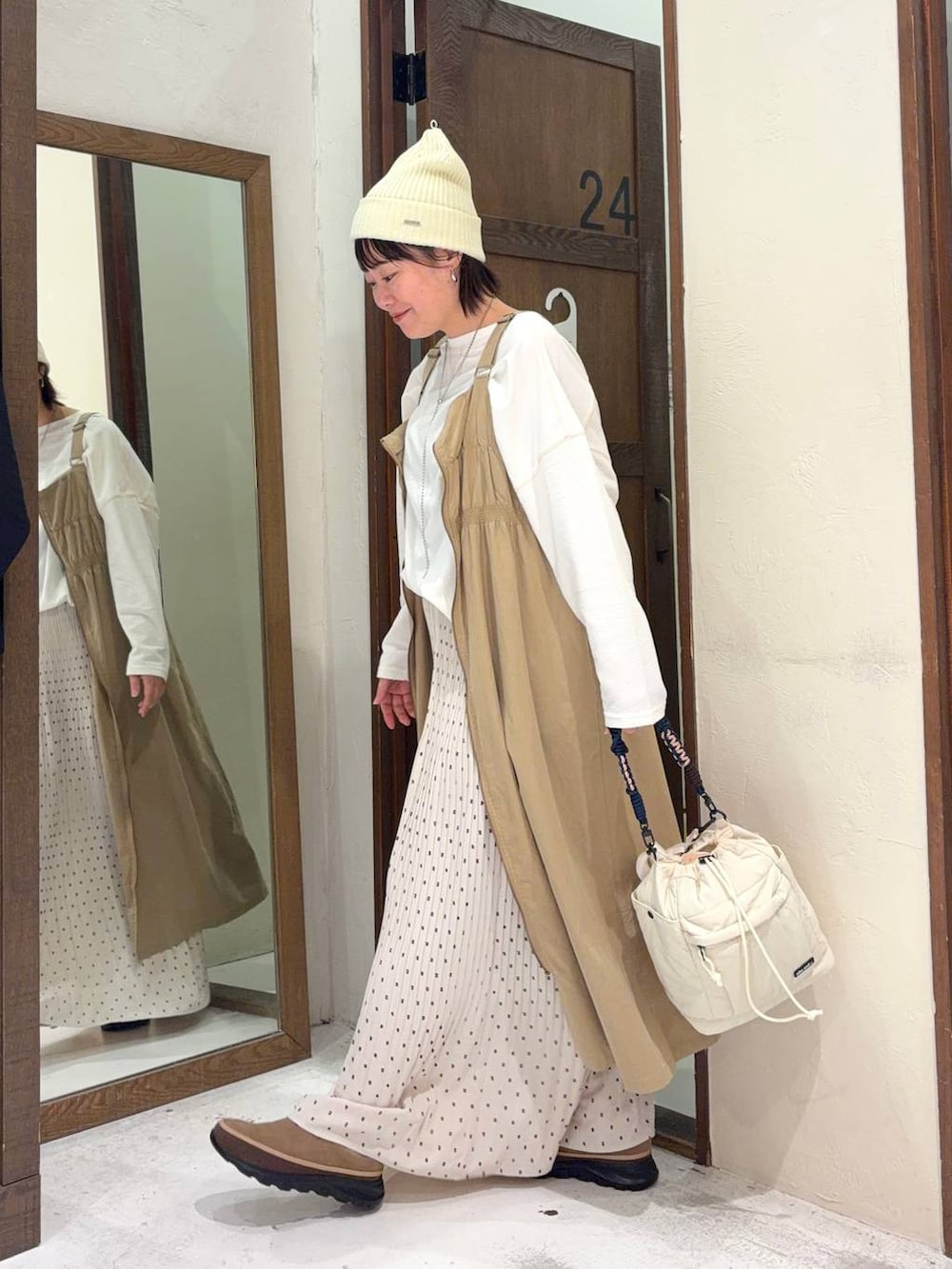 ベージュ系のジャンパースカート、ベージュ系のその他シューズ、ホワイト系のTシャツ/カットソーを着用したレディースの冬コーディネートの2枚目の写真