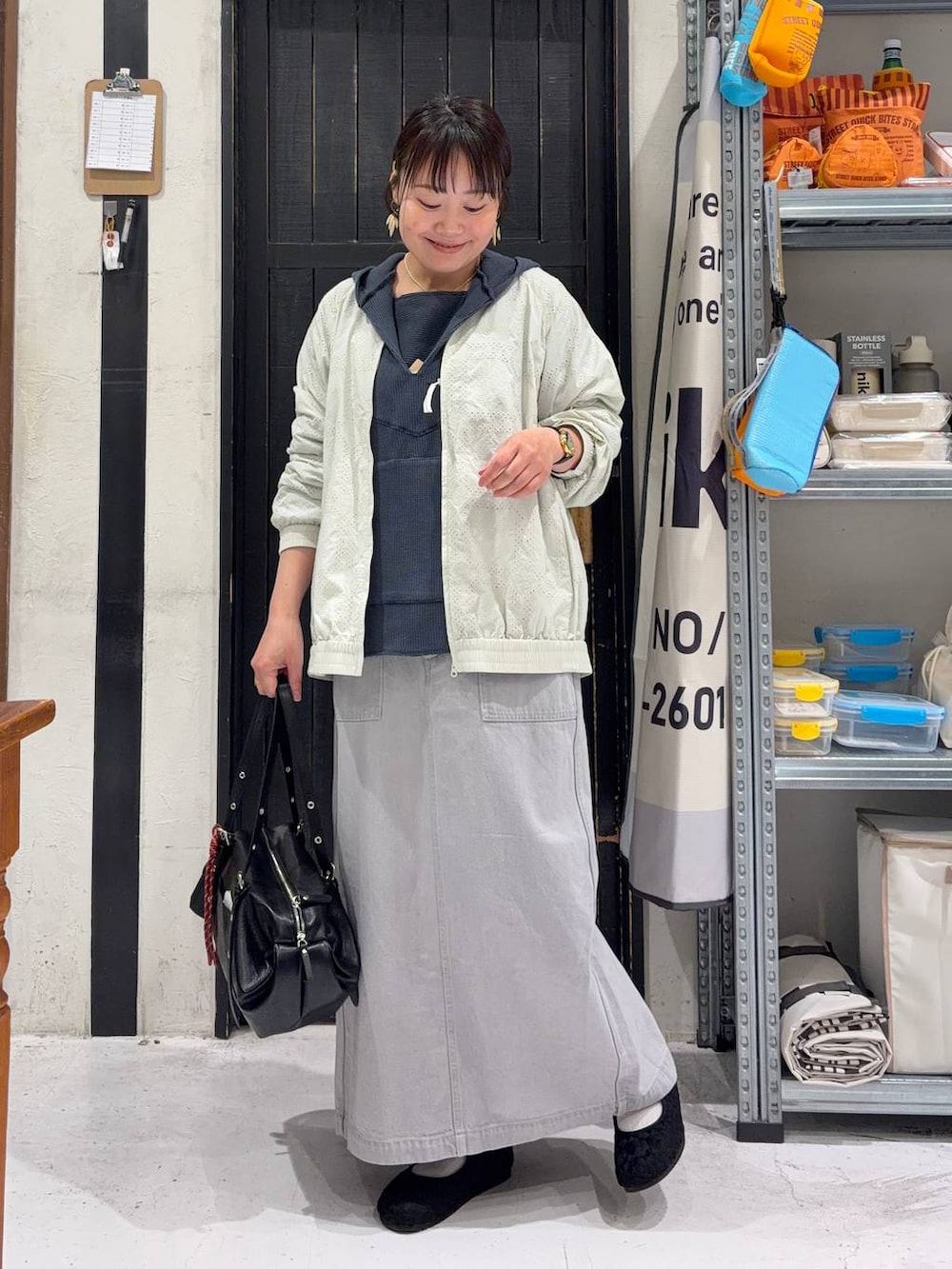 グレー系のスカート、ブラック系のパンプス、ホワイト系のブルゾンを着用したレディースの春コーディネートの2枚目の写真