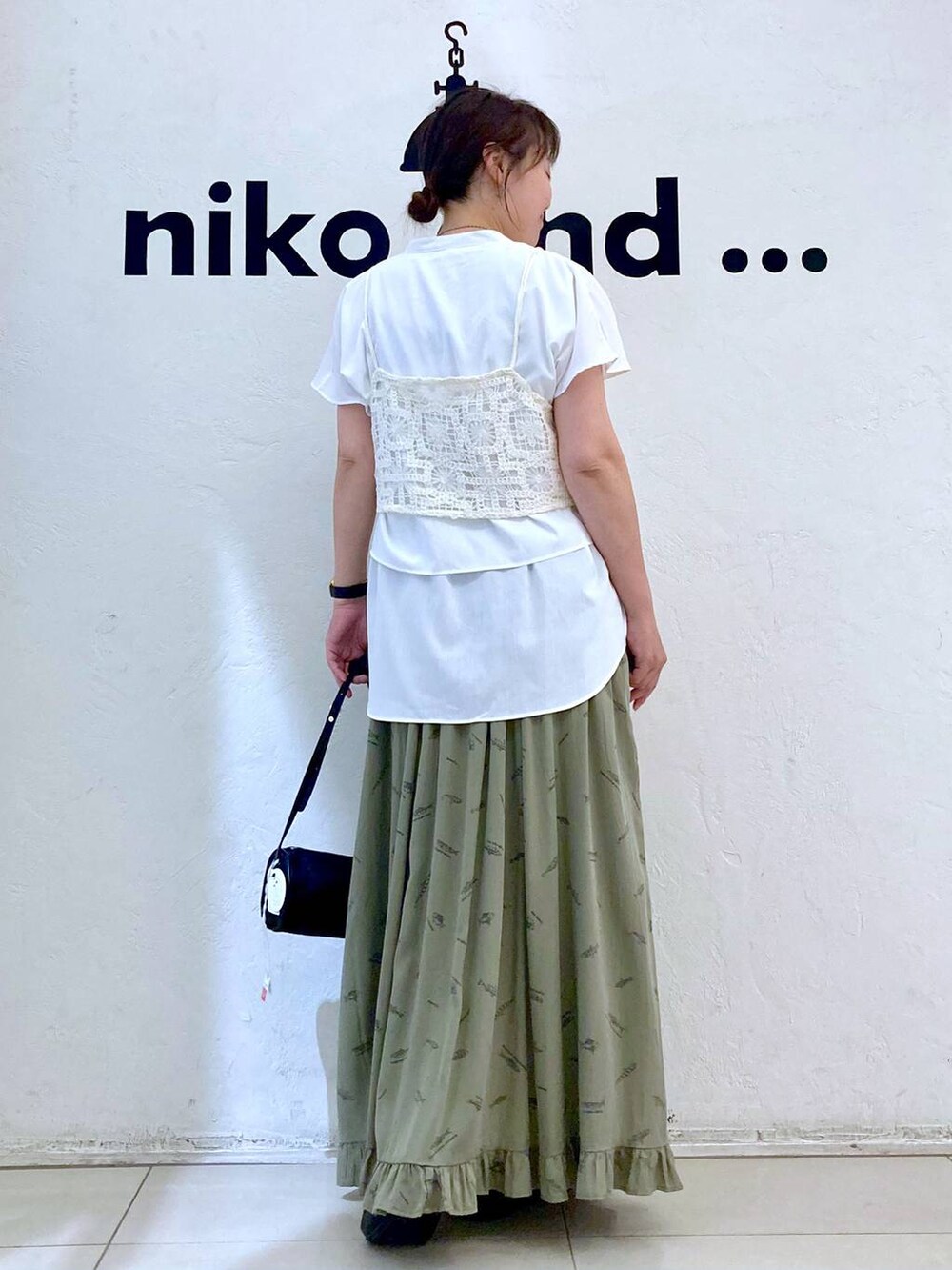 ブラック系のパンプス、ブラック系のショルダーバッグ、グリーン系のスカートを着用したレディースの夏コーディネートの4枚目の写真