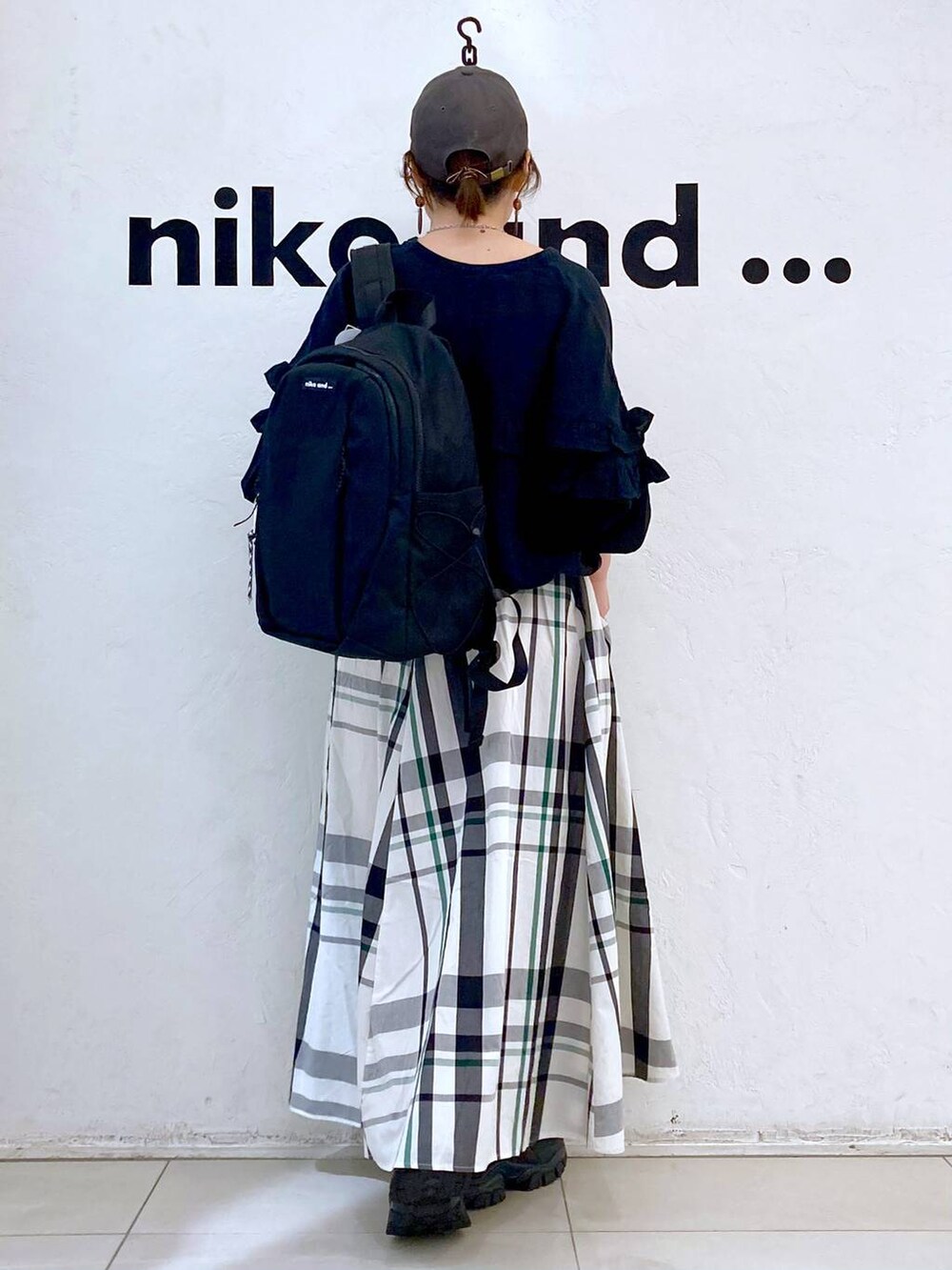 ブラック系のバックパック/リュック、ブラック系のシャツ/ブラウス、ベージュ系のスカートを着用したレディースの春コーディネートの5枚目の写真