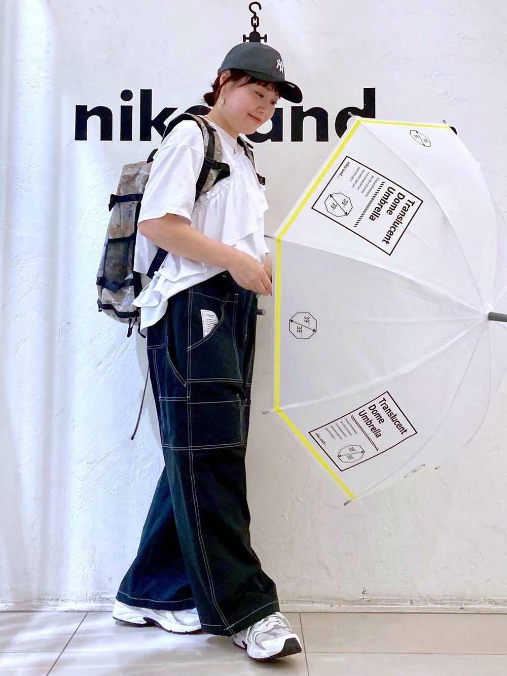 ホワイト系の長傘、グレー系のキャップを着用したレディースの春コーディネートの5枚目の写真