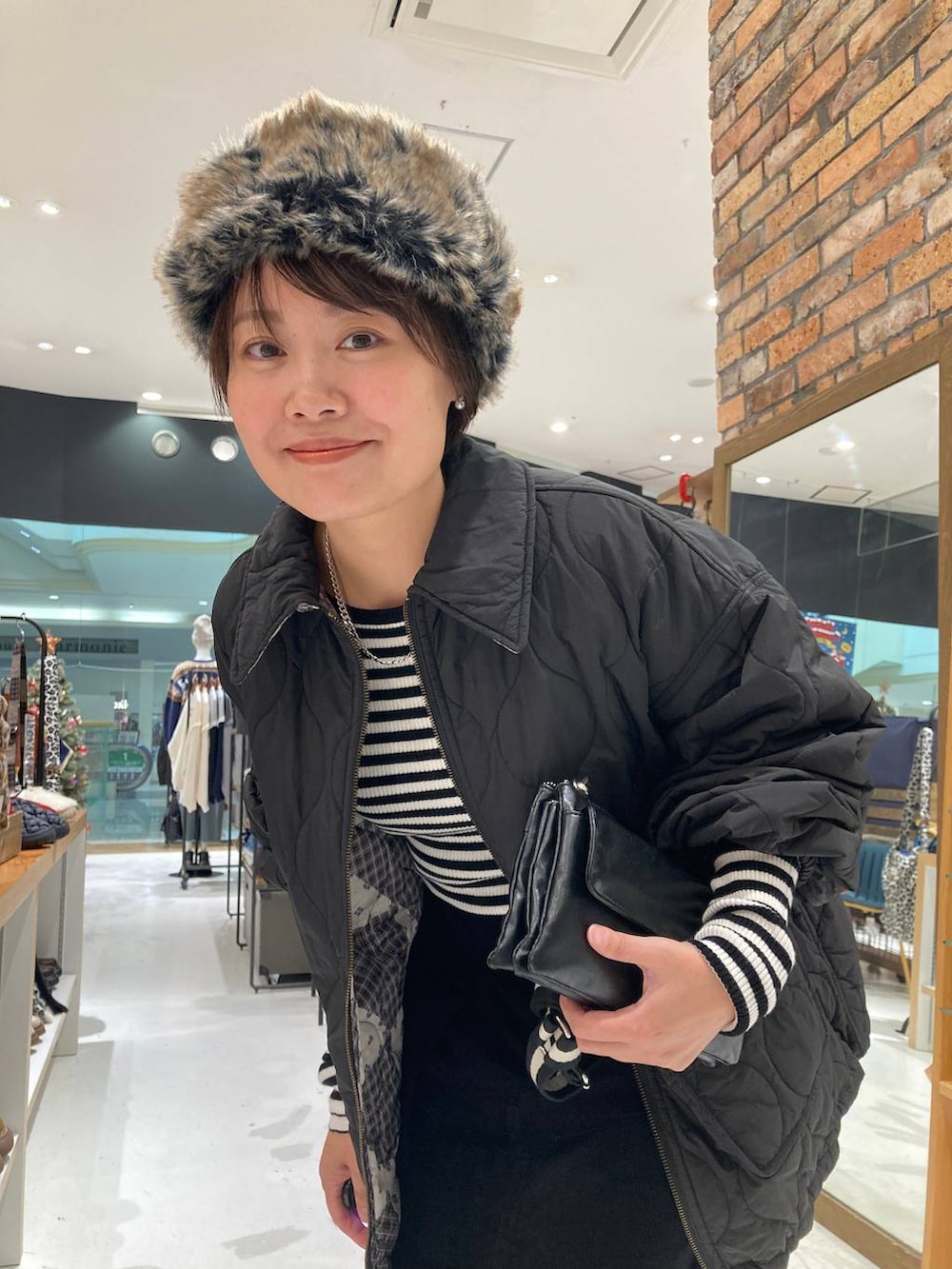 ブラック系のその他アウター、ホワイト系のニット/セーター、ブラック系のショルダーバッグを着用したレディースの冬コーディネートの7枚目の写真