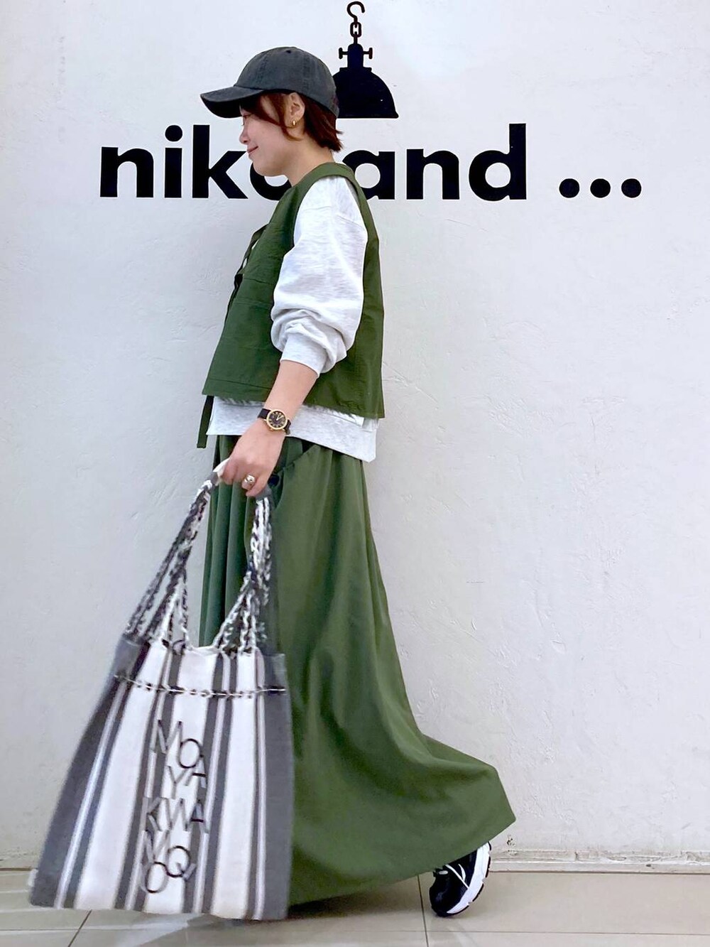 グリーン系のスカート、ベージュ系のTシャツ/カットソー、グリーン系のベストを着用したレディースの春コーディネートの5枚目の写真