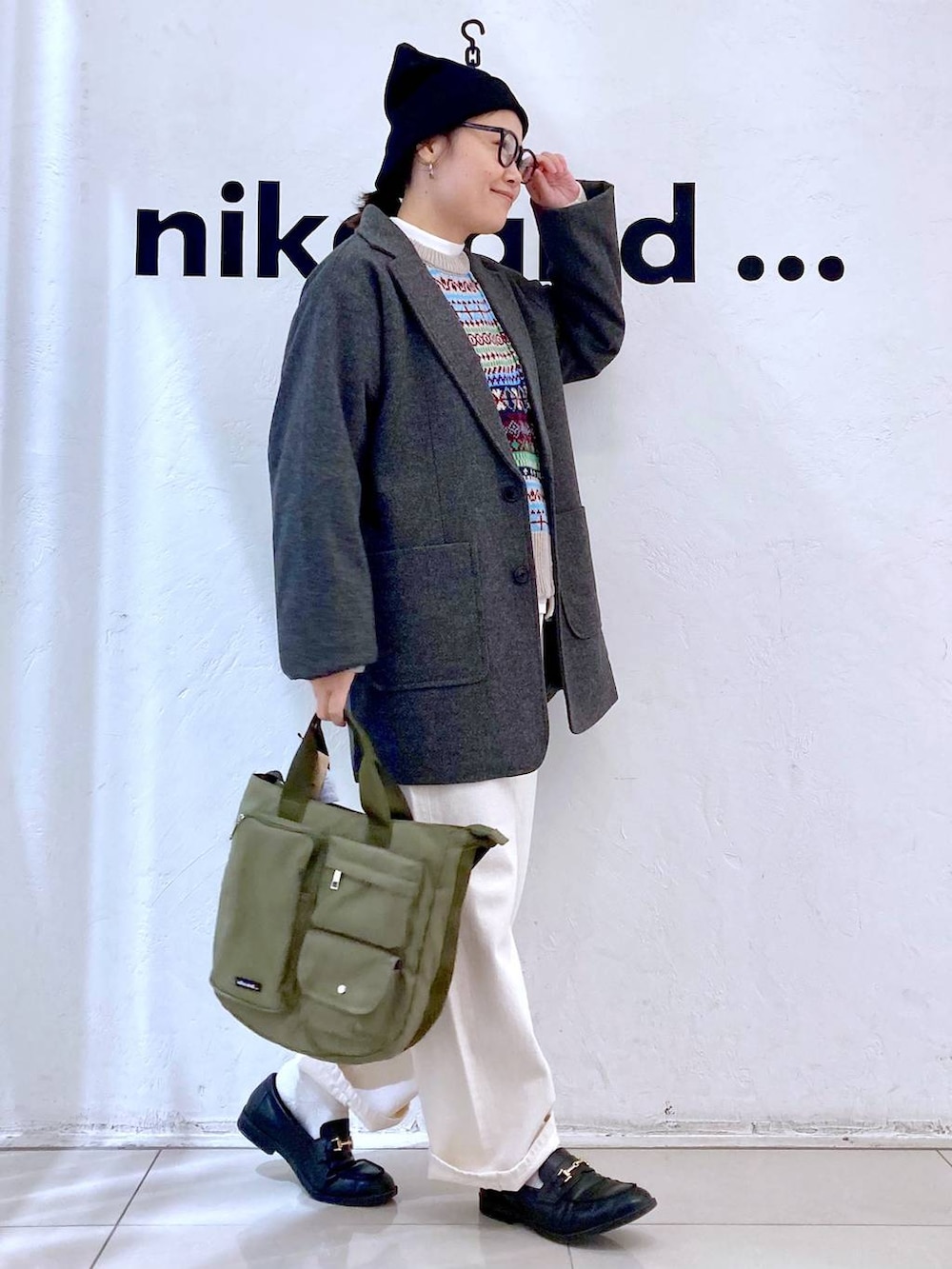 グレー系のテーラードジャケット、ホワイト系のTシャツ/カットソー、グリーン系のトートバッグを着用したレディースの冬コーディネートの3枚目の写真