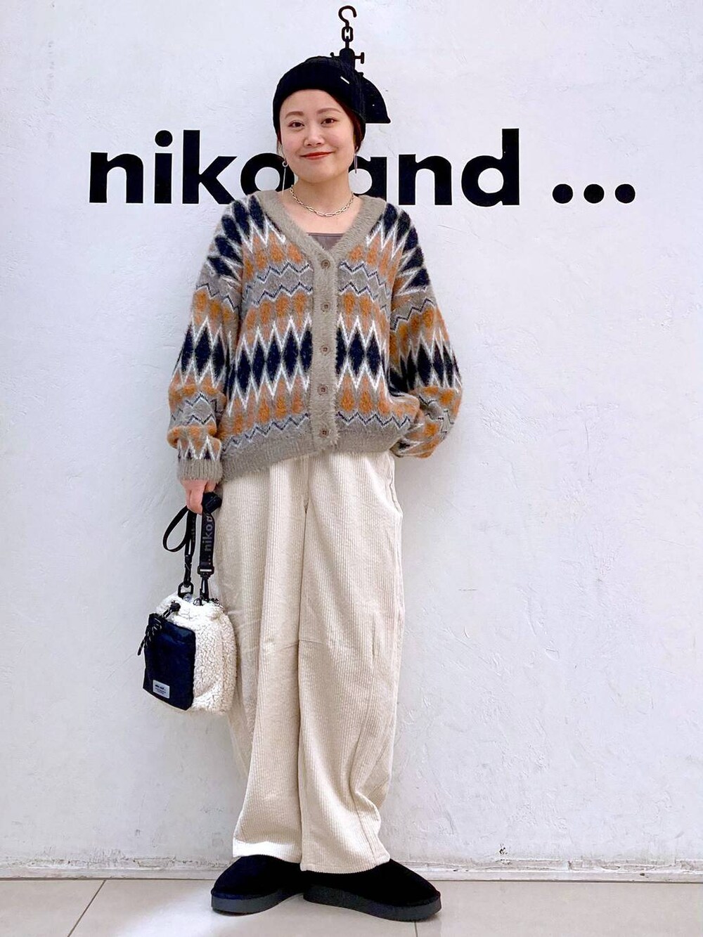 ブラウン系のカーディガン/ボレロ、ブラック系のブーツ、ベージュ系のショルダーバッグを着用したレディースの冬コーディネートの5枚目の写真