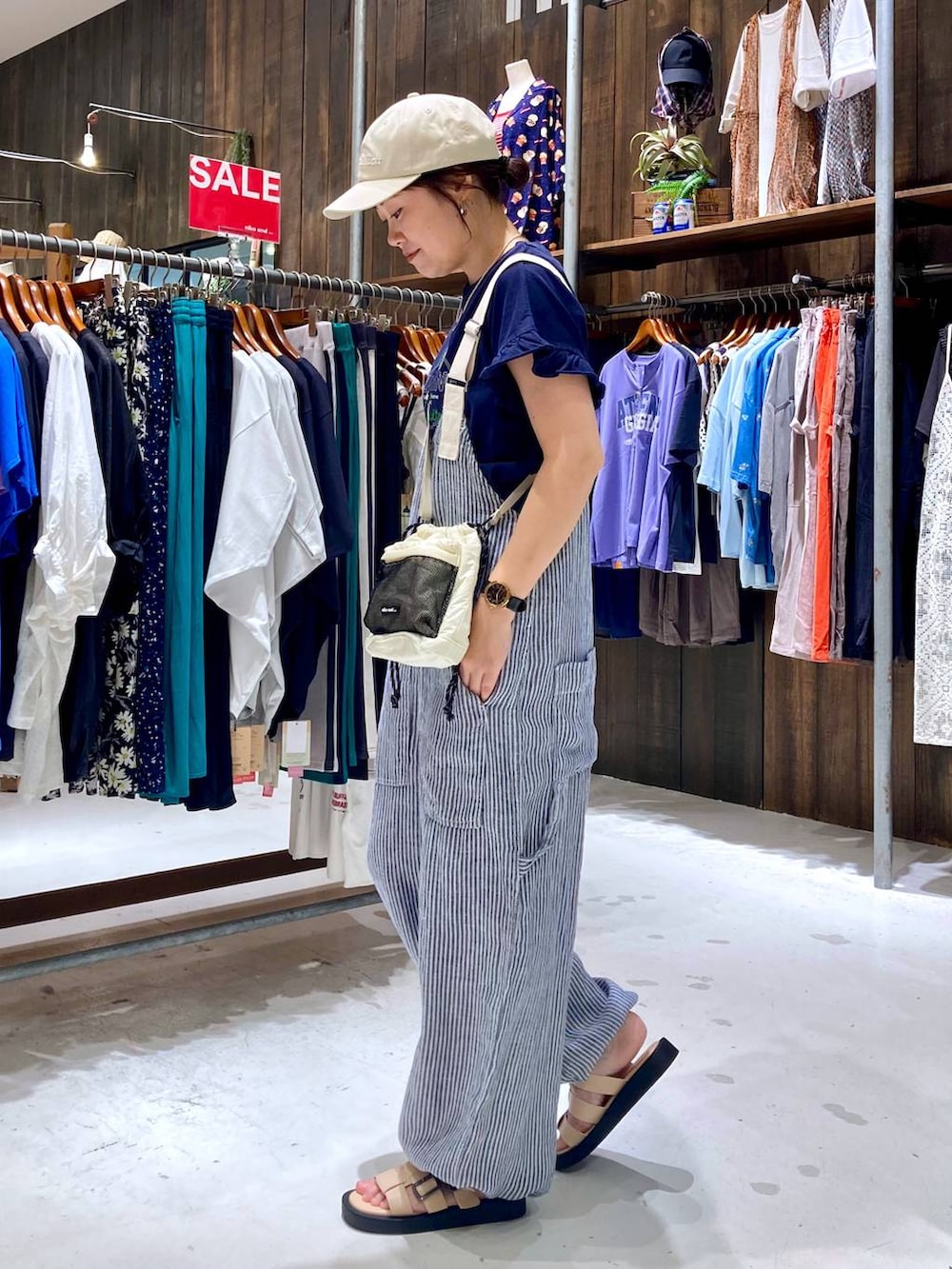 ブルー系のサロペット/オーバーオール、ブルー系のTシャツ/カットソー、ベージュ系のショルダーバッグを着用したレディースの夏コーディネートの3枚目の写真