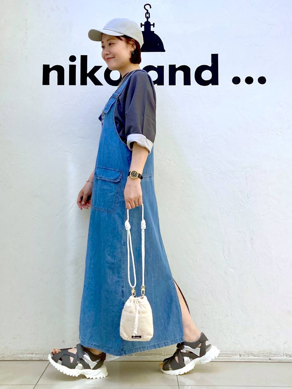 ホワイト系のショルダーバッグ、グレー系のTシャツ/カットソー、ブルー系のジャンパースカートを着用したレディースの夏コーディネートの5枚目の写真