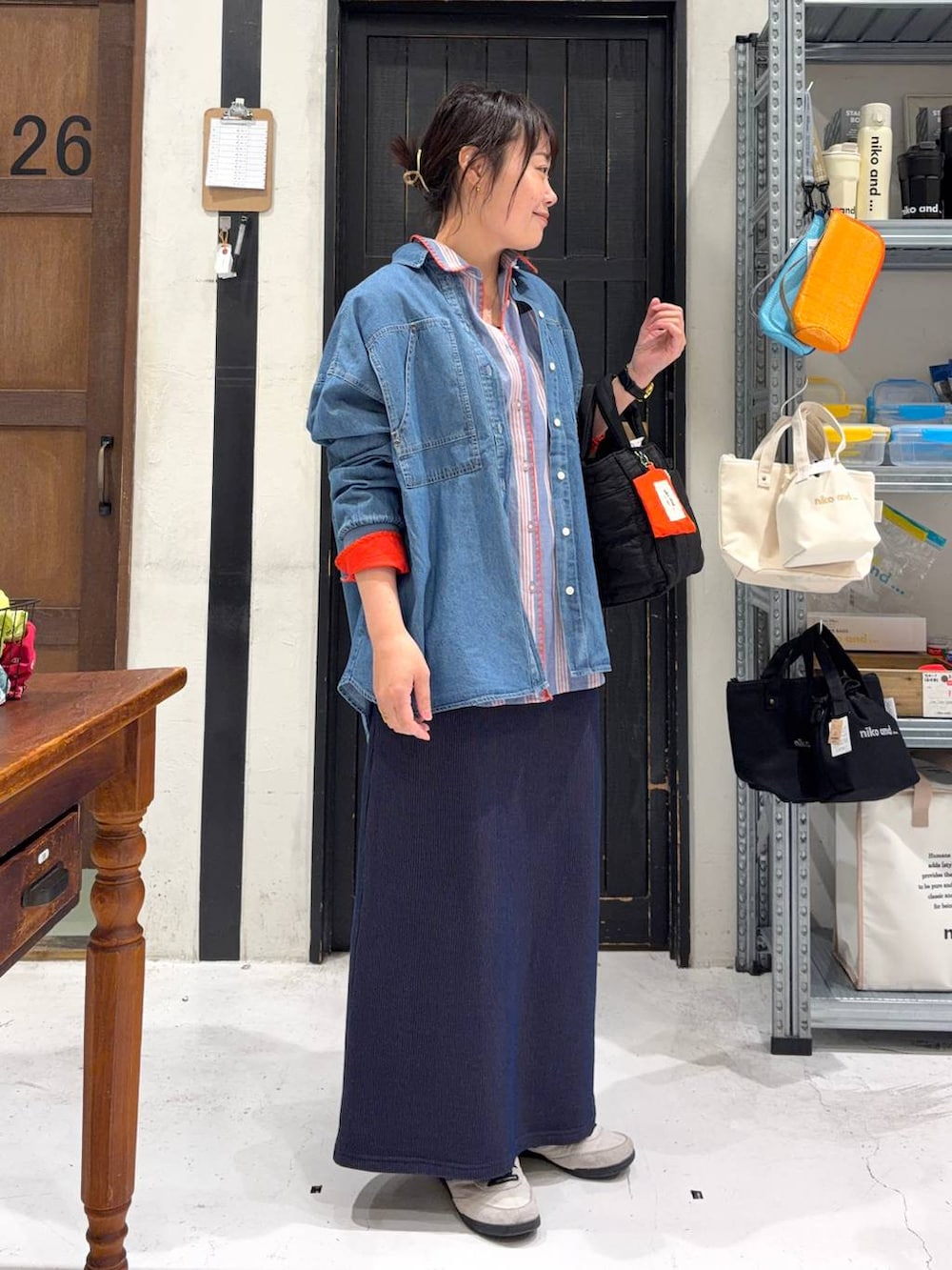 ブラック系のトートバッグ、ブルー系のスカート、その他のネックレスを着用したレディースの春コーディネートの5枚目の写真