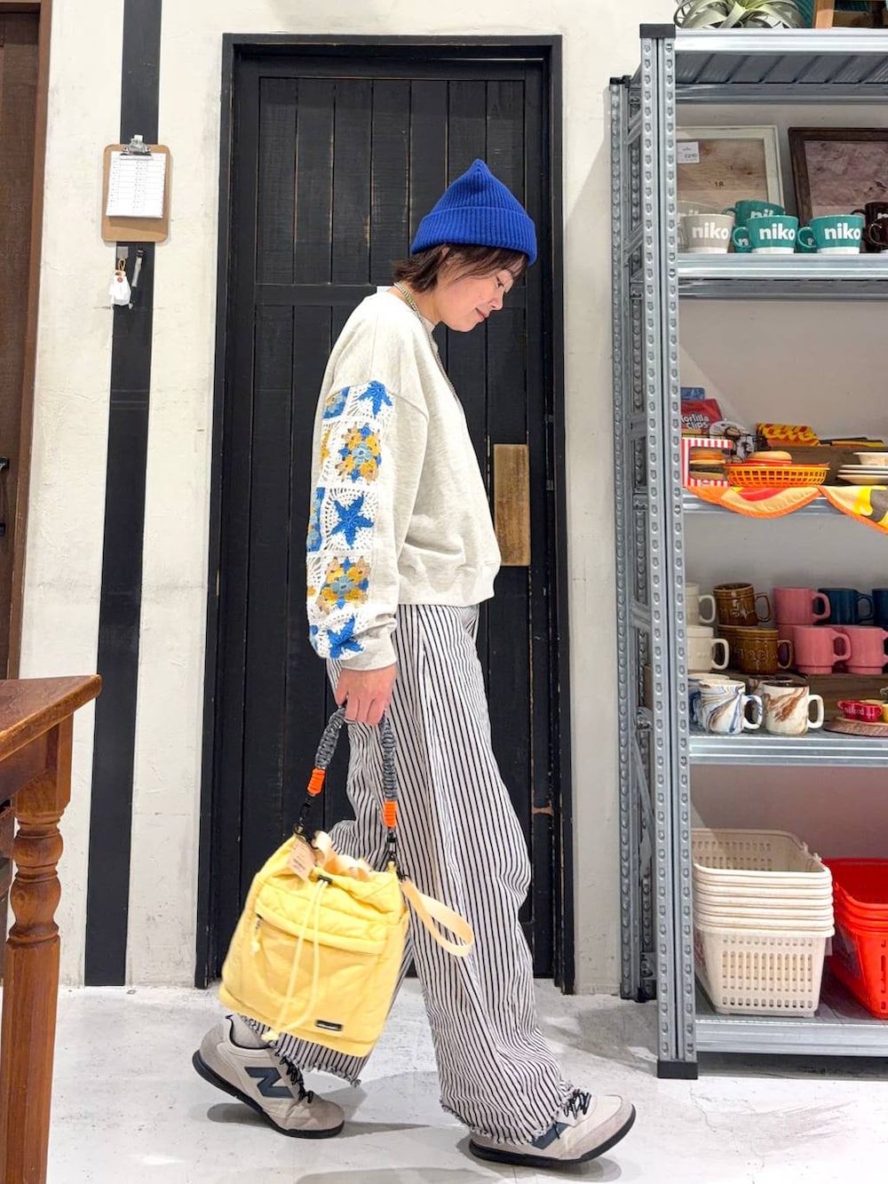 イエロー系のショルダーバッグ、ホワイト系のデニムパンツ、ブルー系のニットキャップ/ビーニーを着用したレディースの冬コーディネートの5枚目の写真