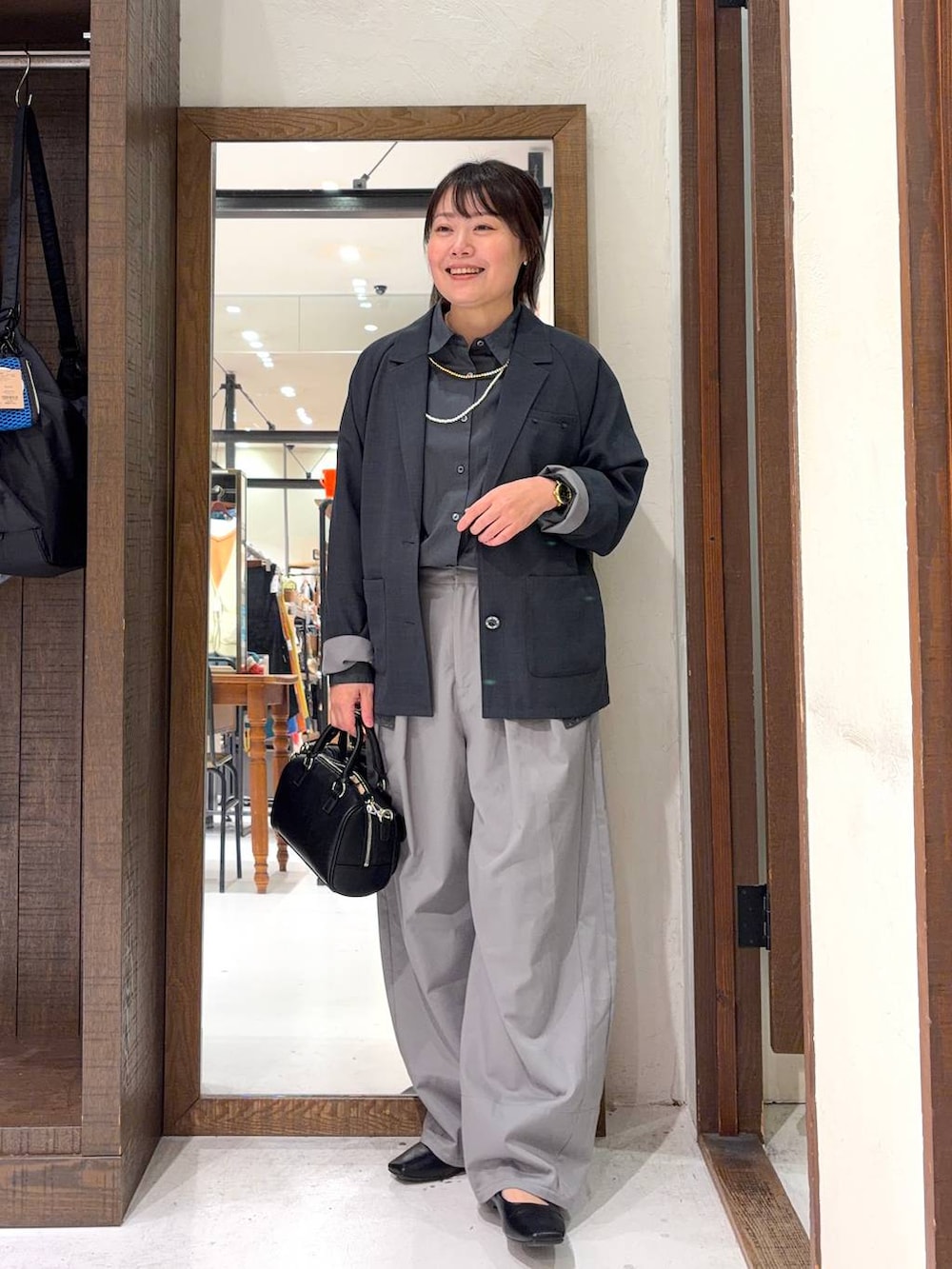 ブラック系のボストンバッグ、グレー系のシャツ/ブラウス、イエロー系のネックレスを着用したレディースの冬コーディネートの2枚目の写真