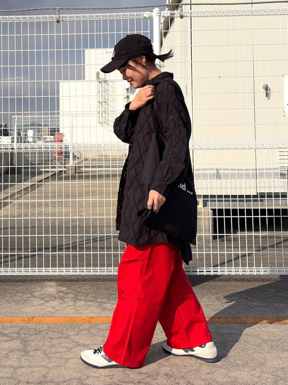 ブラック系のトートバッグ、ブラック系のチュニック、オレンジ系のその他パンツを着用したレディースの春コーディネートの4枚目の写真