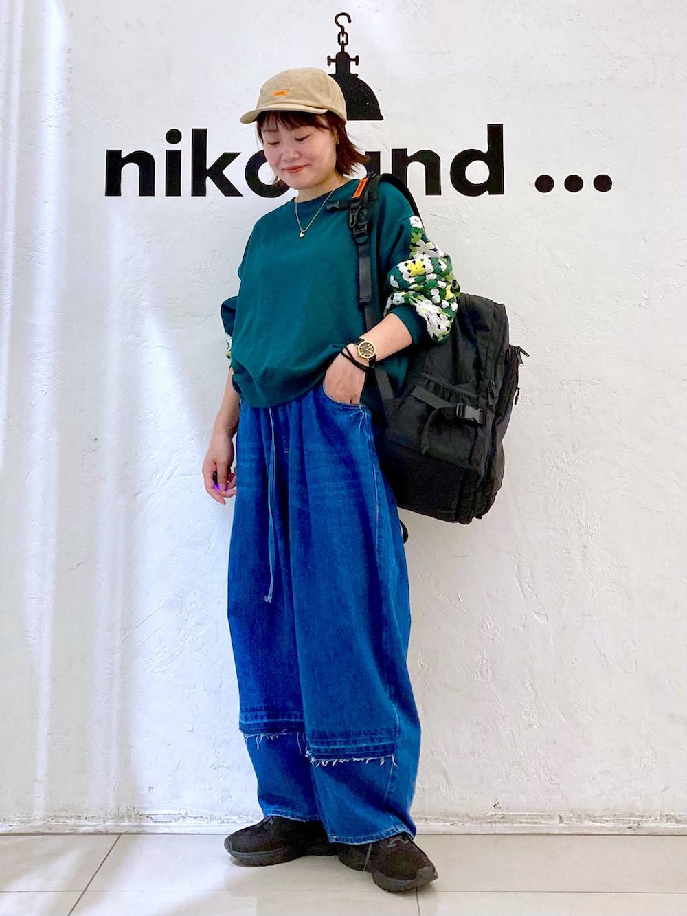 グリーン系のスウェット、ブルー系のデニムパンツ、ブラック系のバックパック/リュックを着用したレディースの秋コーディネートの2枚目の写真