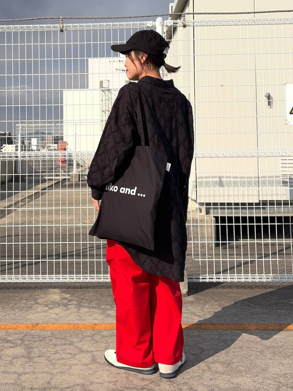 ブラック系のトートバッグ、ブラック系のチュニック、オレンジ系のその他パンツを着用したレディースの春コーディネートの5枚目の写真