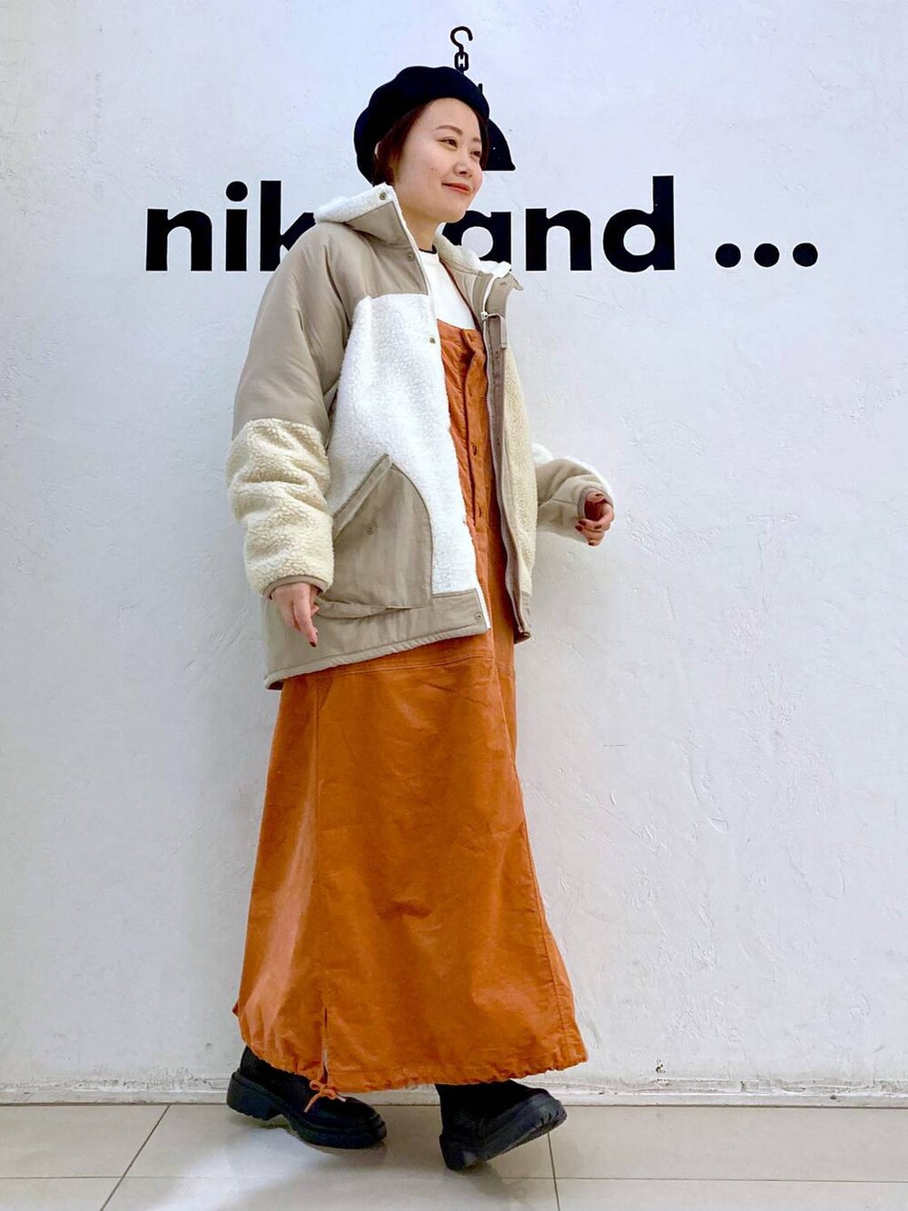 ベージュ系のその他アウター、ホワイト系のニット/セーター、ブラック系のブーツを着用したレディースの冬コーディネートの4枚目の写真