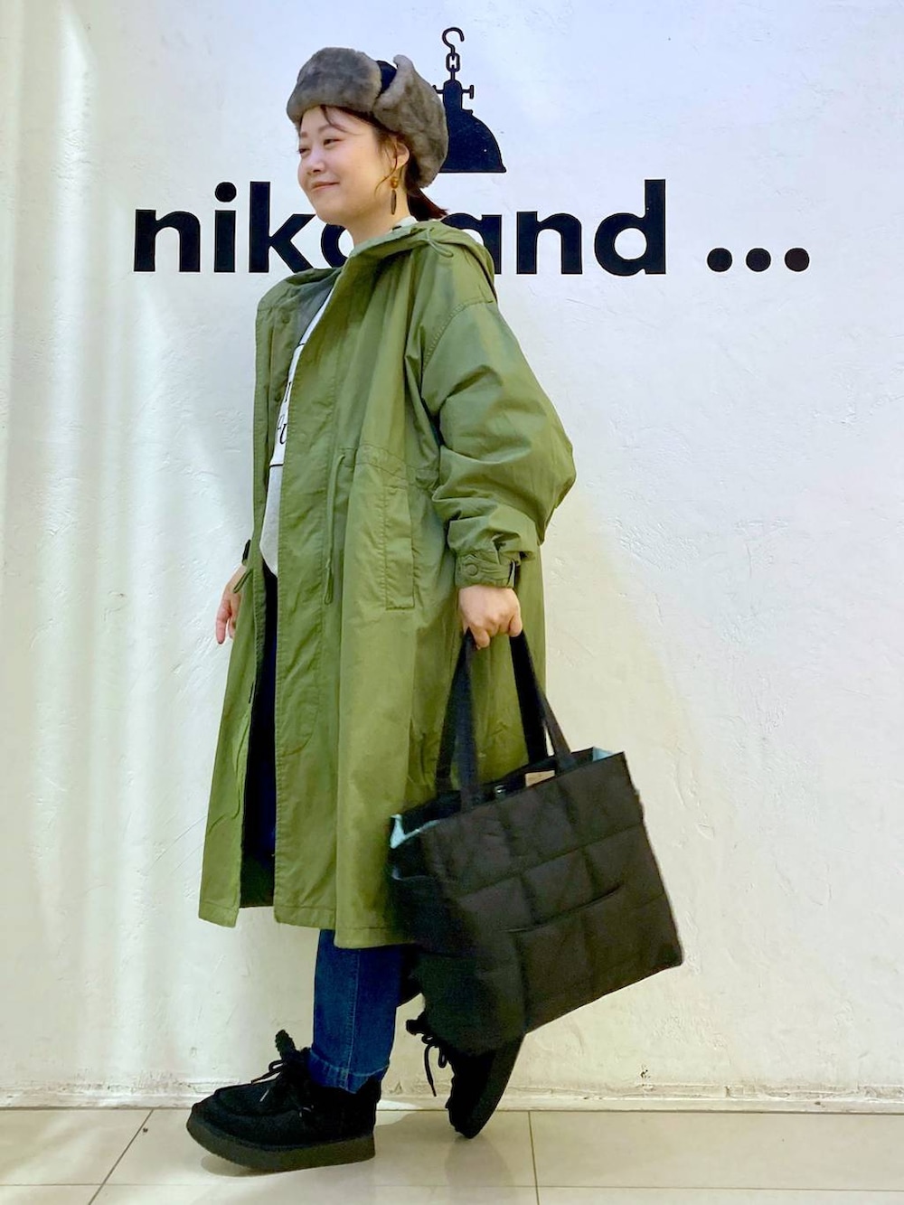 グリーン系のモッズコート、ブルー系のその他パンツ、ブラック系のトートバッグを着用したレディースの冬コーディネートの3枚目の写真