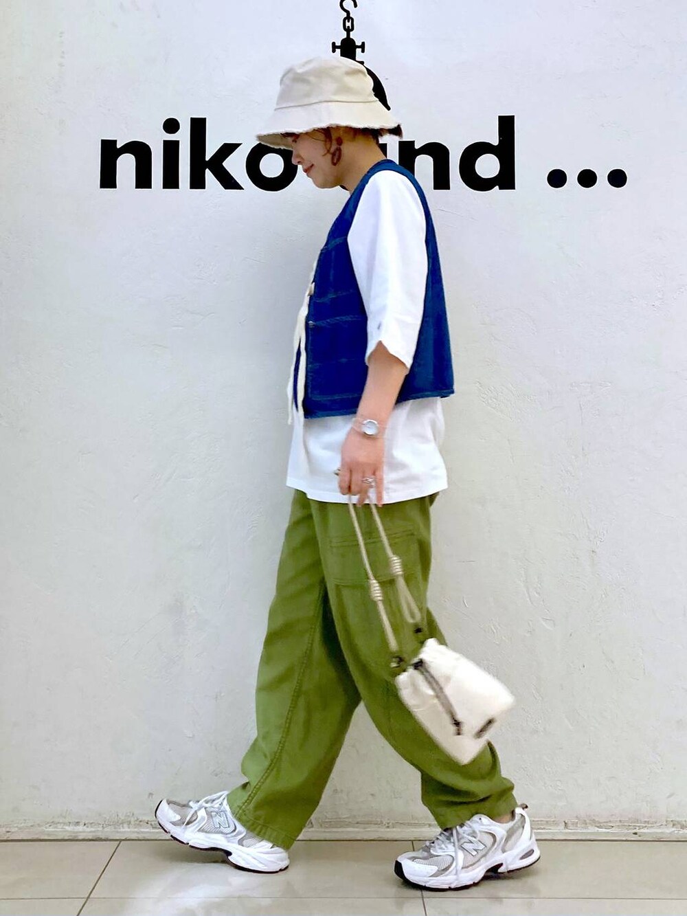 ブルー系のベスト、ベージュ系のショルダーバッグ、グリーン系のカーゴパンツを着用したレディースの春コーディネートの5枚目の写真