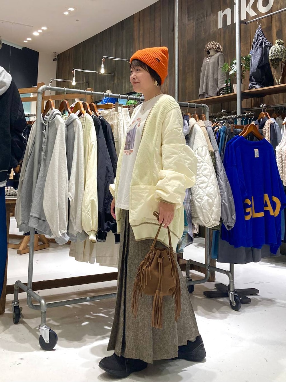 ブラウン系のスカート、ブラウン系のショルダーバッグ、ホワイト系のTシャツ/カットソーを着用したレディースの秋コーディネートの3枚目の写真