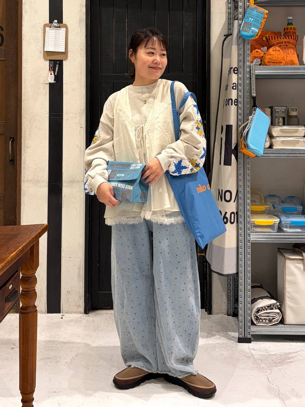 ベージュ系のスウェット、ブルー系のトートバッグ、ブルー系のデニムパンツを着用したレディースの春コーディネートの2枚目の写真