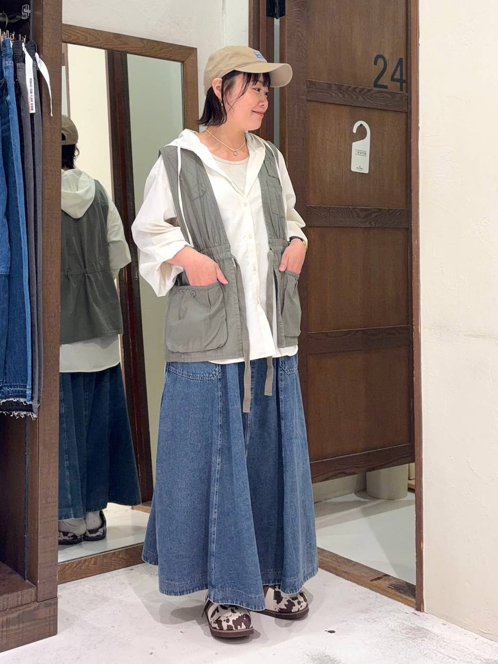 ブルー系のスカート、グリーン系のベスト、ホワイト系のシャツ/ブラウスを着用したレディースの春コーディネートの2枚目の写真