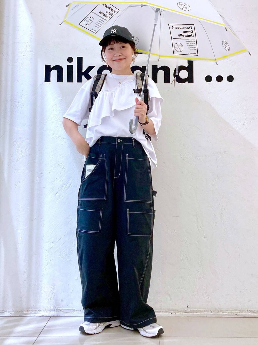ホワイト系の長傘、グレー系のキャップを着用したレディースの春コーディネートの2枚目の写真
